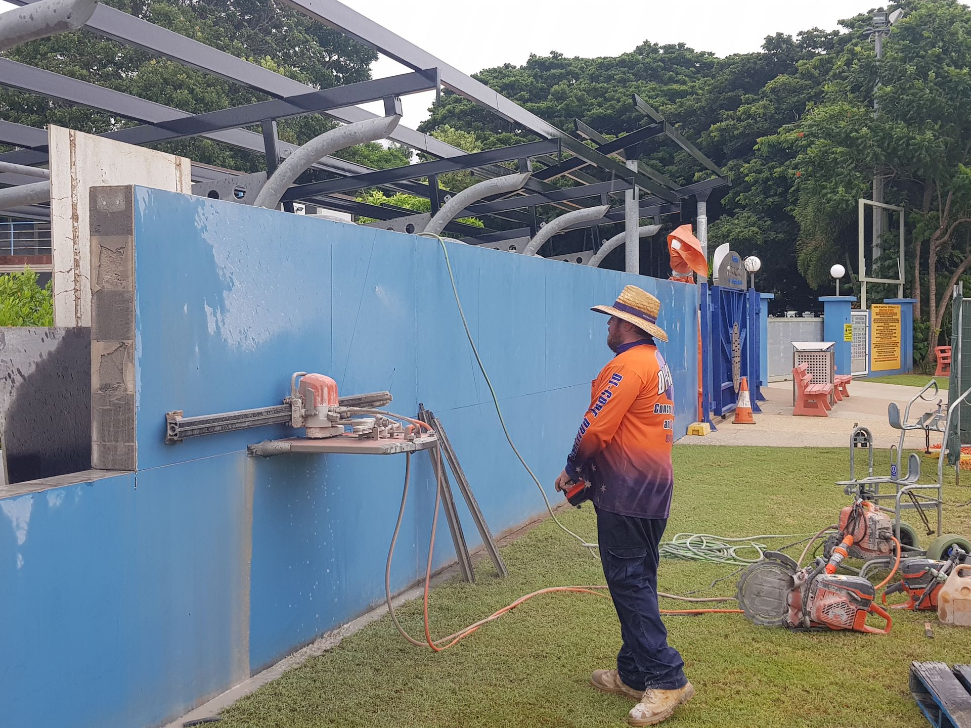Man using a concrete saw to cut a hole in a blue wall — Di-Core Drilling and Cutting in Darwin, NT