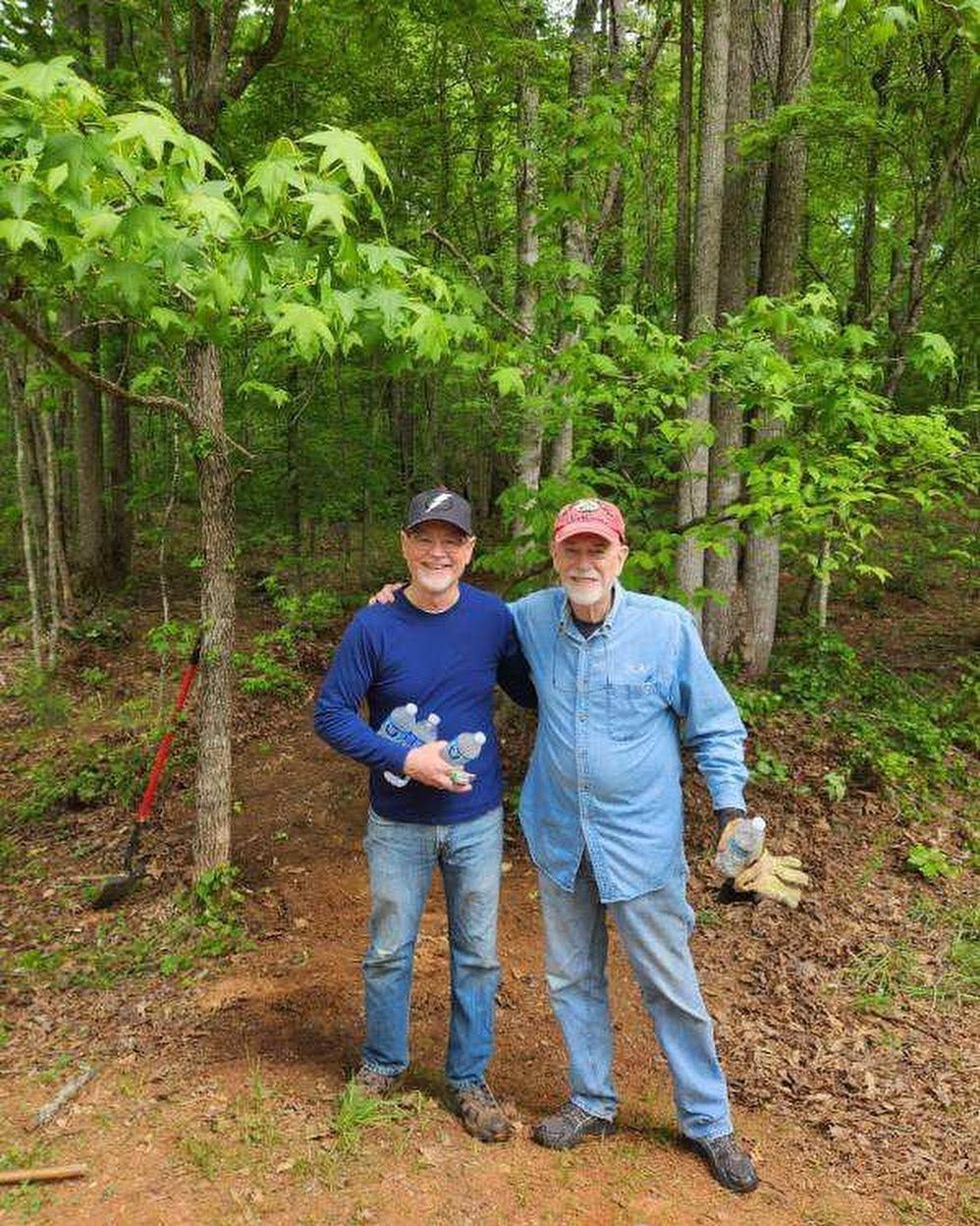 Two volunteers standing together on a wooded Grace Valley trail.