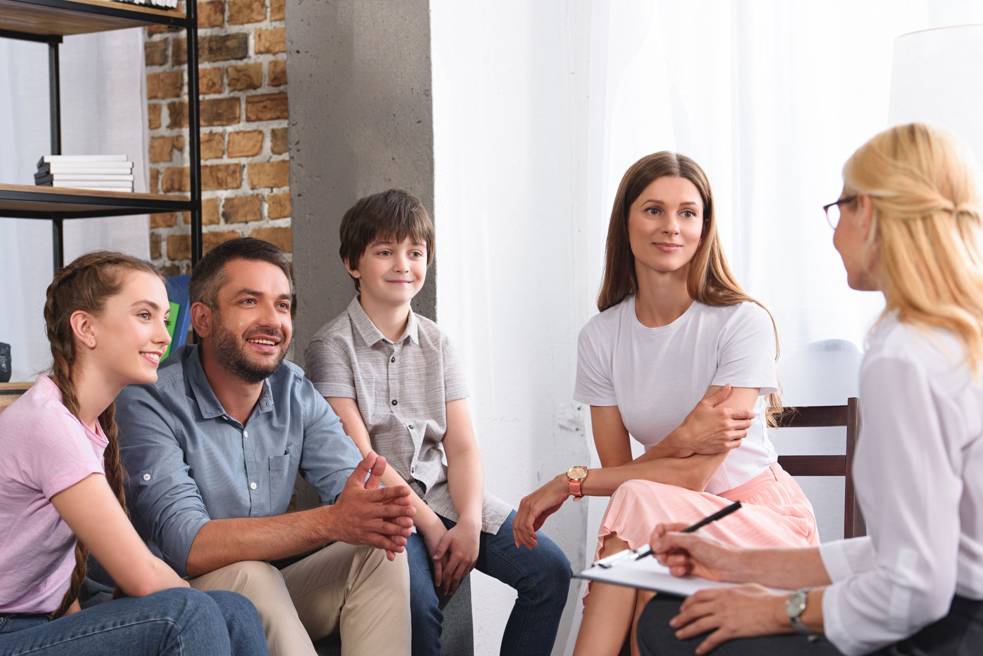 Small group in a counseling session, seated and talking with a therapist in a bright office