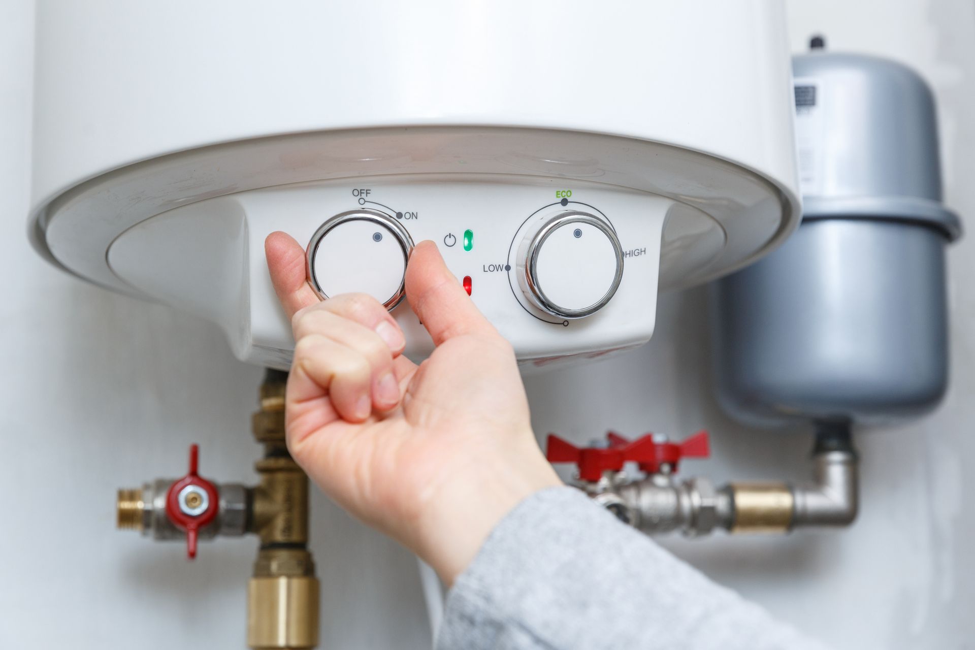 A person is adjusting the temperature of a water heater.