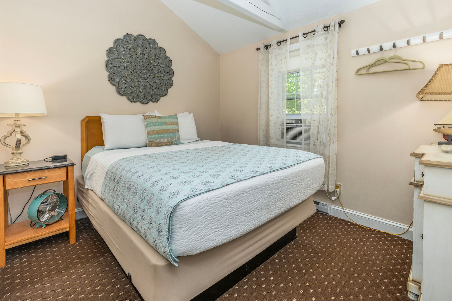 Bedroom with a bed, nightstand, window, and decorative wall art.