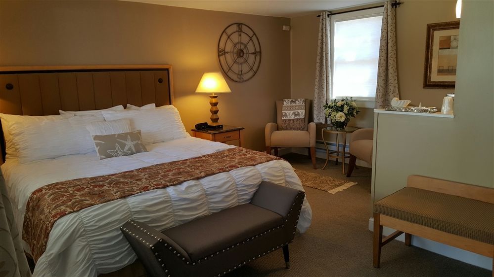 Cozy bedroom with a king-sized bed, two armchairs, a small table, and a bench in front of the bed.