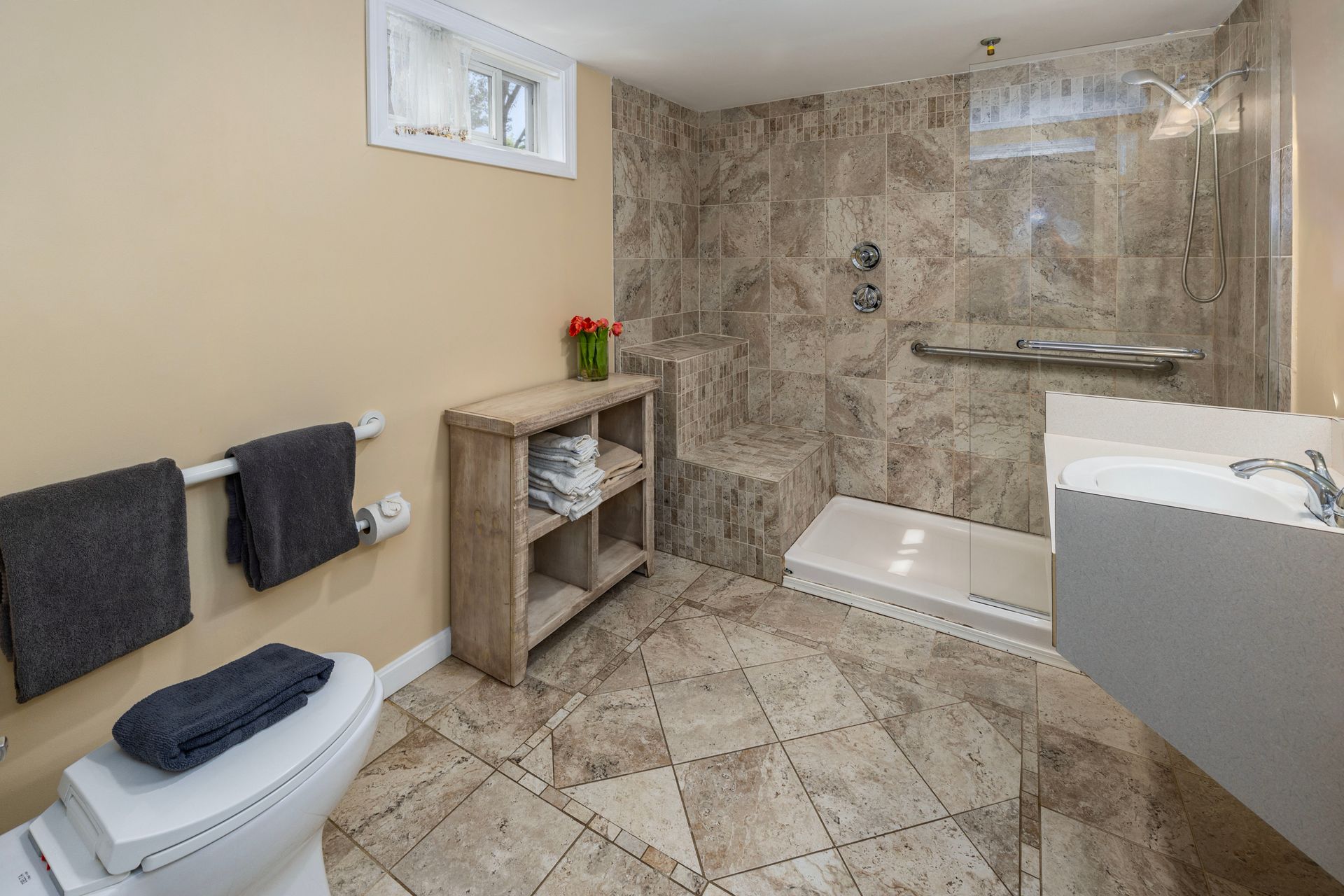 Bathroom with beige walls, shower, toilet, and towel rack. Light brown floor tiles and shower tile.