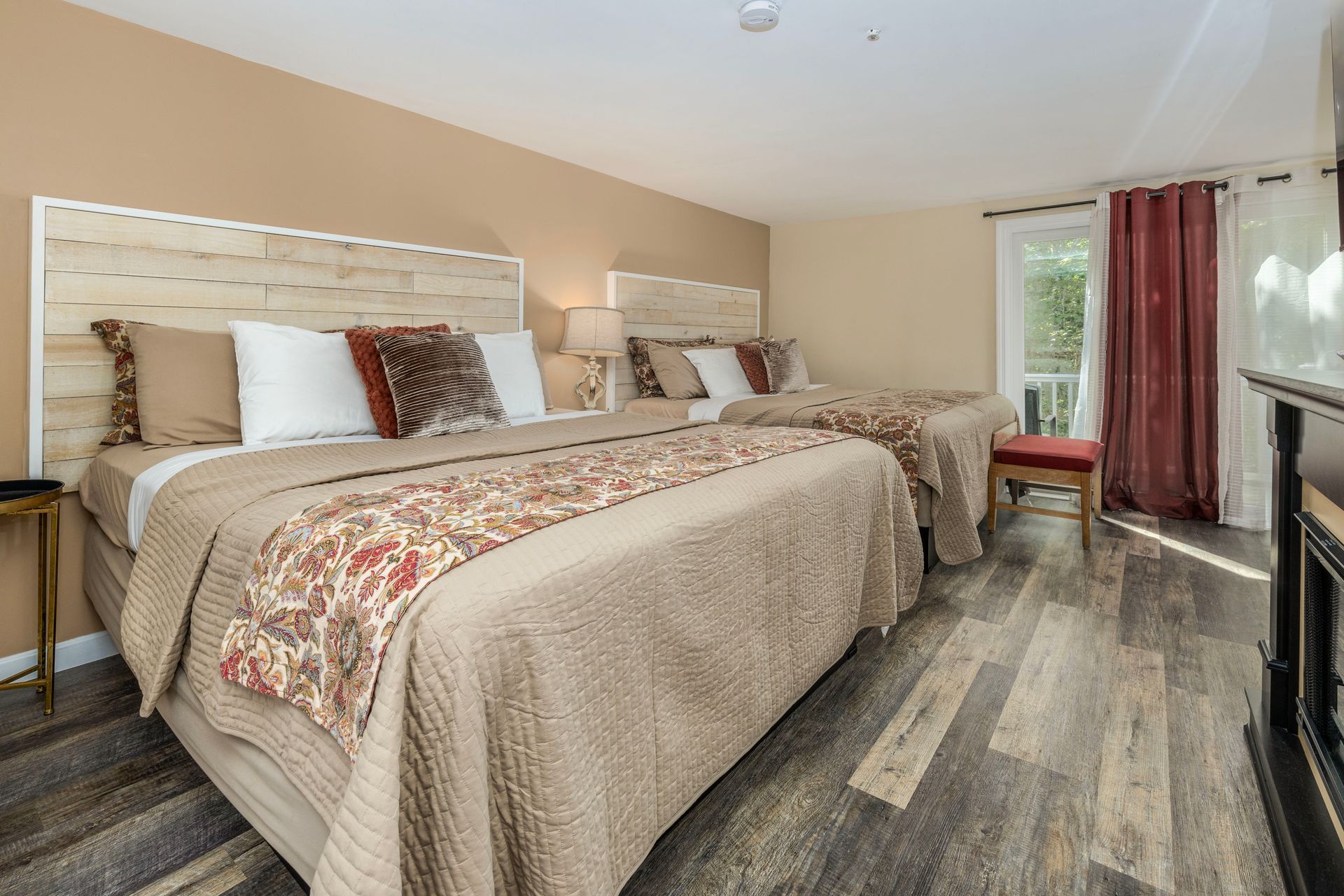 Bedroom with two queen beds, neutral tones, wooden headboards, and a balcony door.