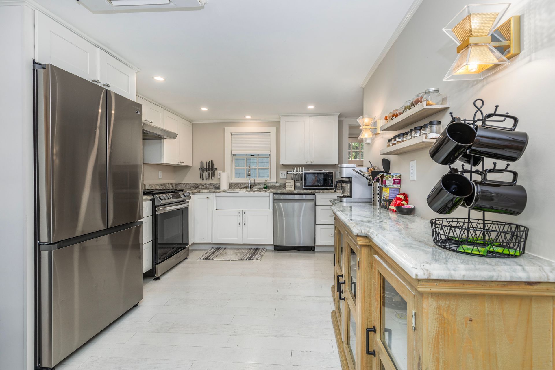 Bright kitchen with stainless steel appliances, white cabinets, and a wooden countertop with marble finish.