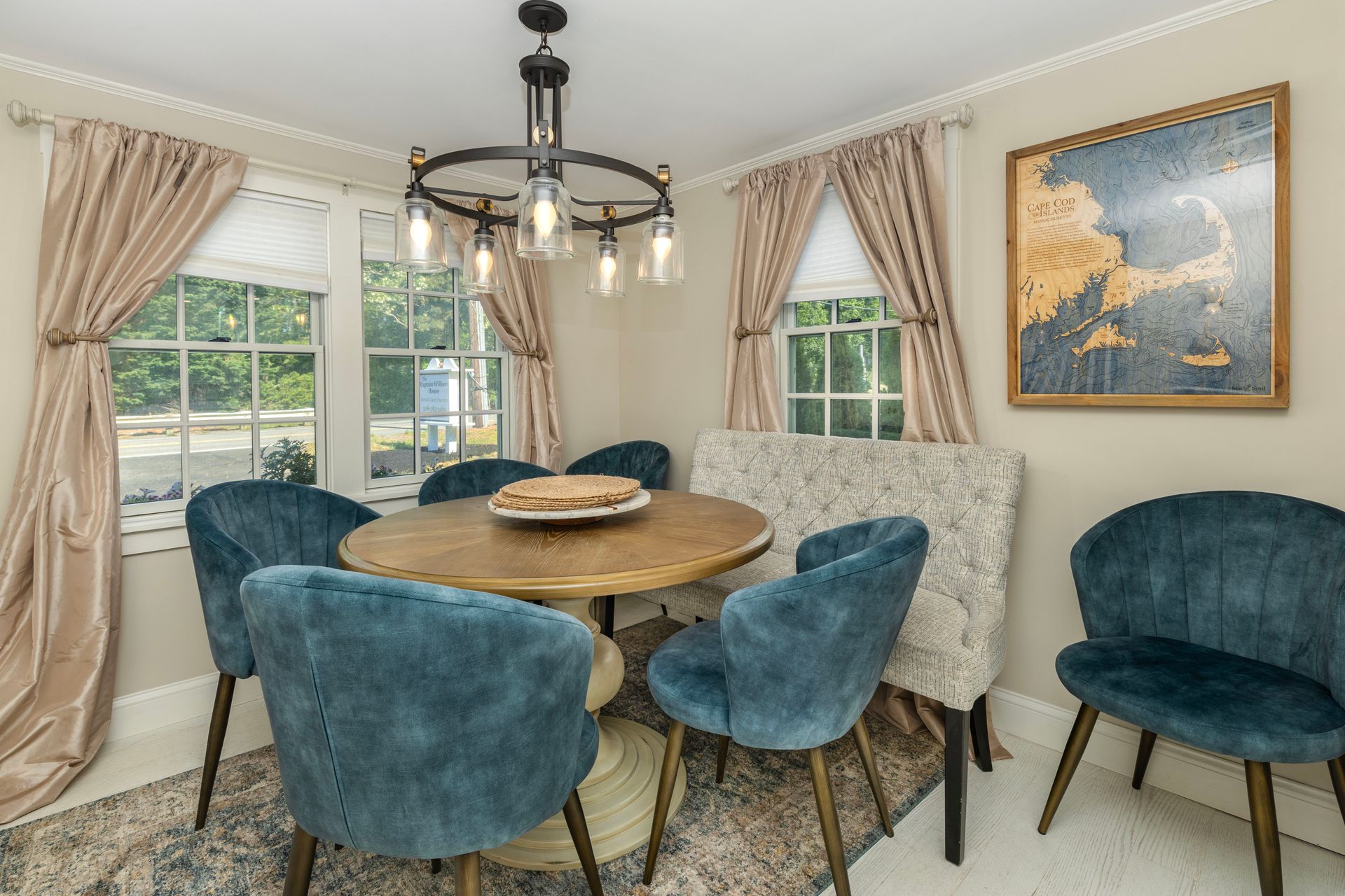 Dining room with a round wooden table, blue chairs, and a decorative light fixture.