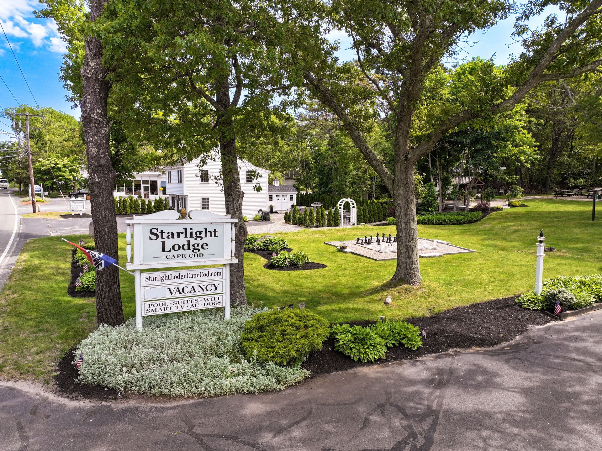 Starlight Lodge sign in front of a white building, with trees and a green lawn on a sunny day.