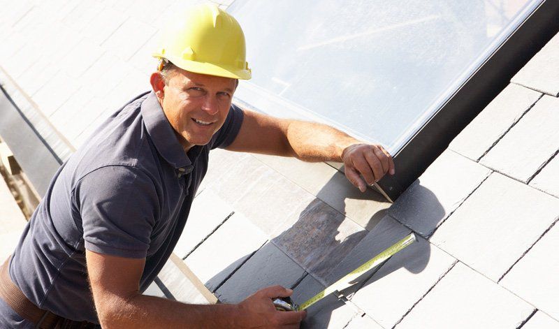 A man is working on a roof with the words roof replacement above him