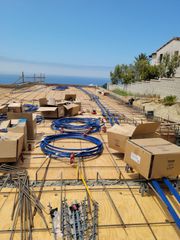 Construction site with blue hoses and cardboard boxes on a rebar deck by the sea
