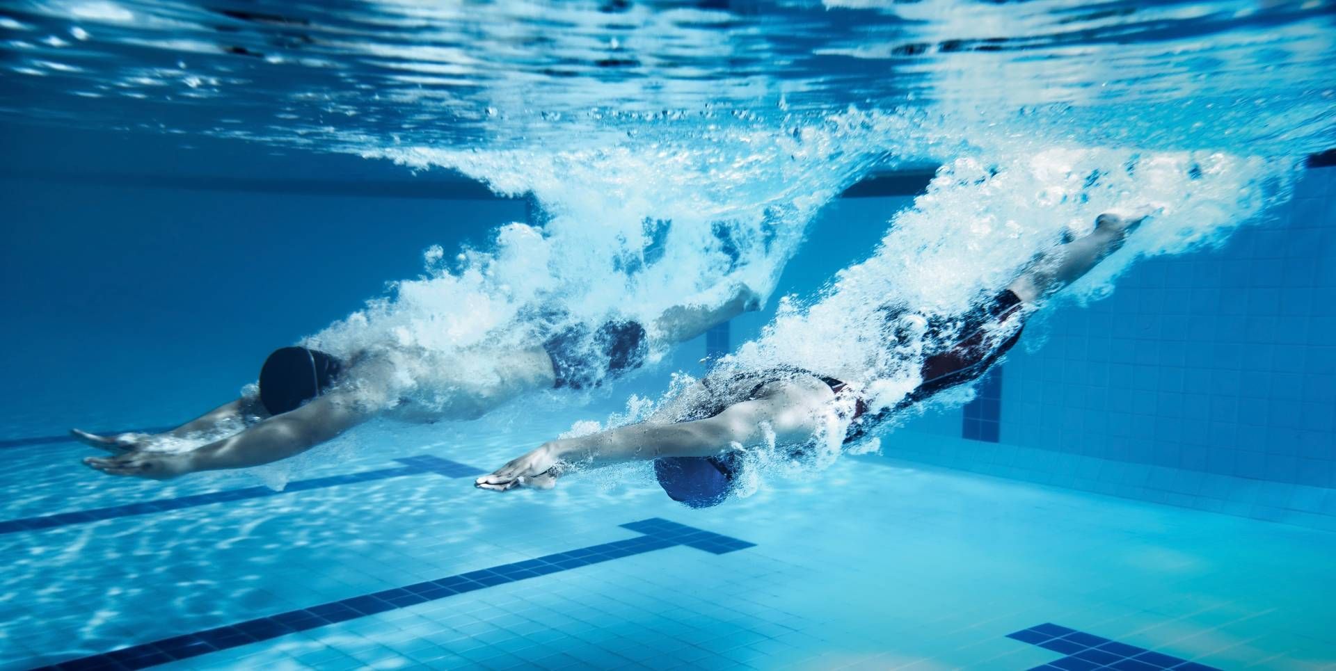 Competitive swimmers diving into lanes from a platform.