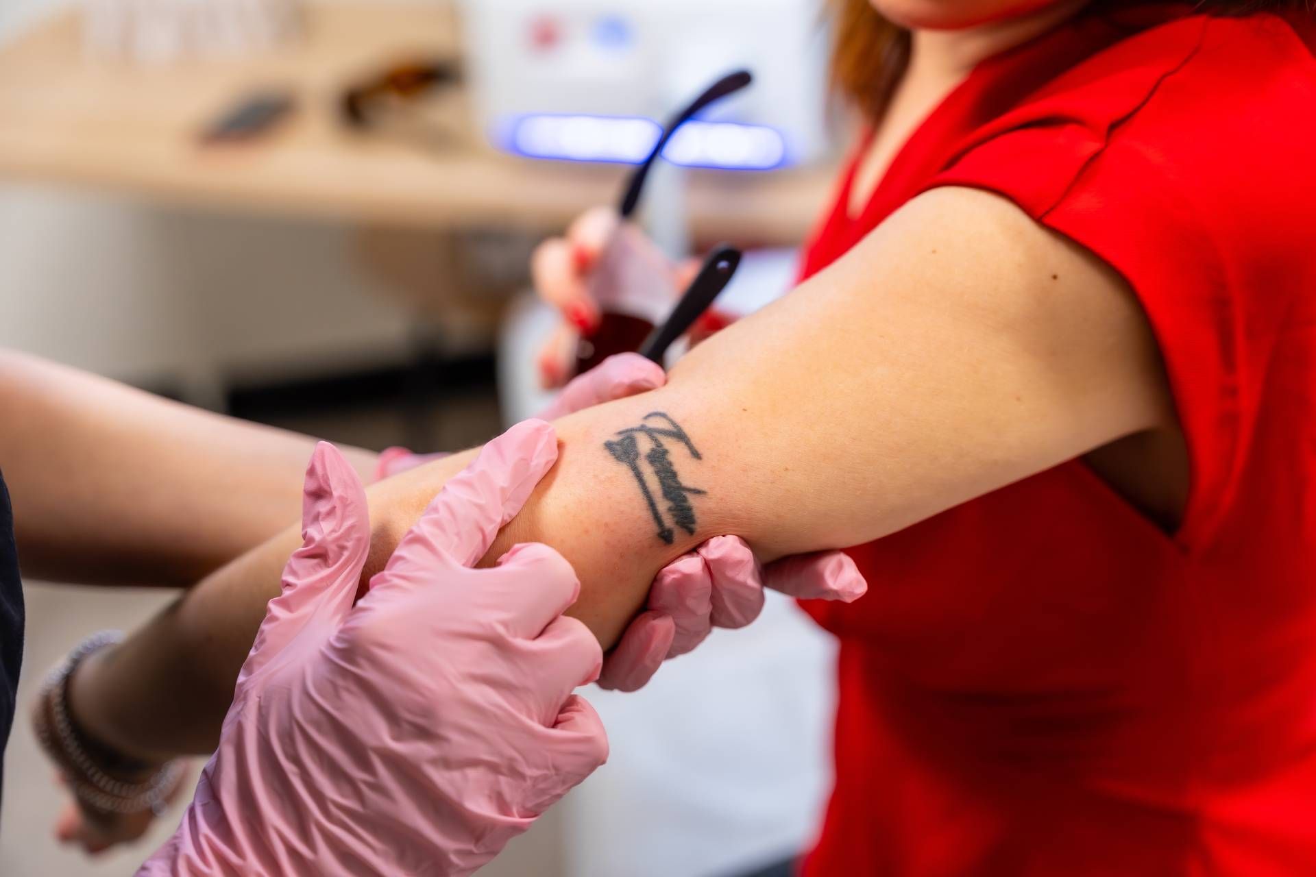 Certified Laser Tattoo Removal Specialist examining a tattoo for removal.