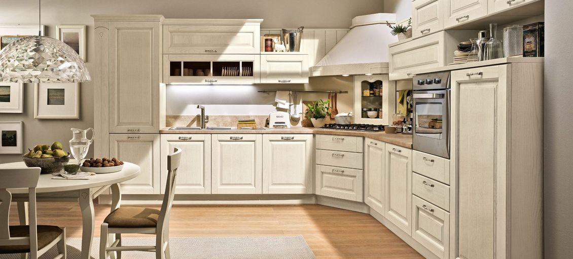 Una cucina con mobili bianchi, tavolo e sedie.