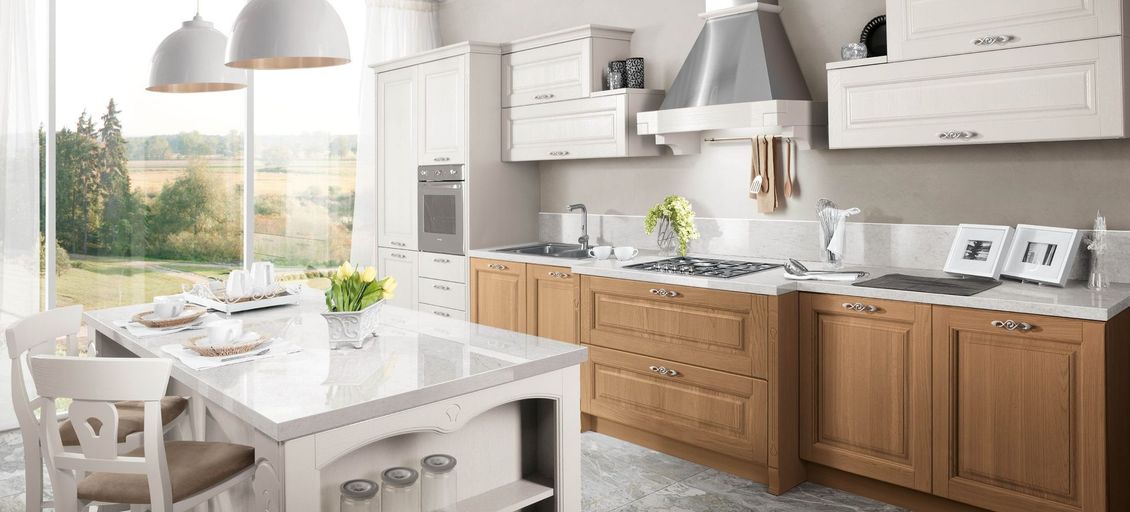 Una cucina con mobili in legno, ripiani bianchi e una grande isola.