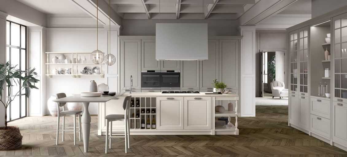 Una cucina con mobili bianchi, fornello, tavolo e sedie.