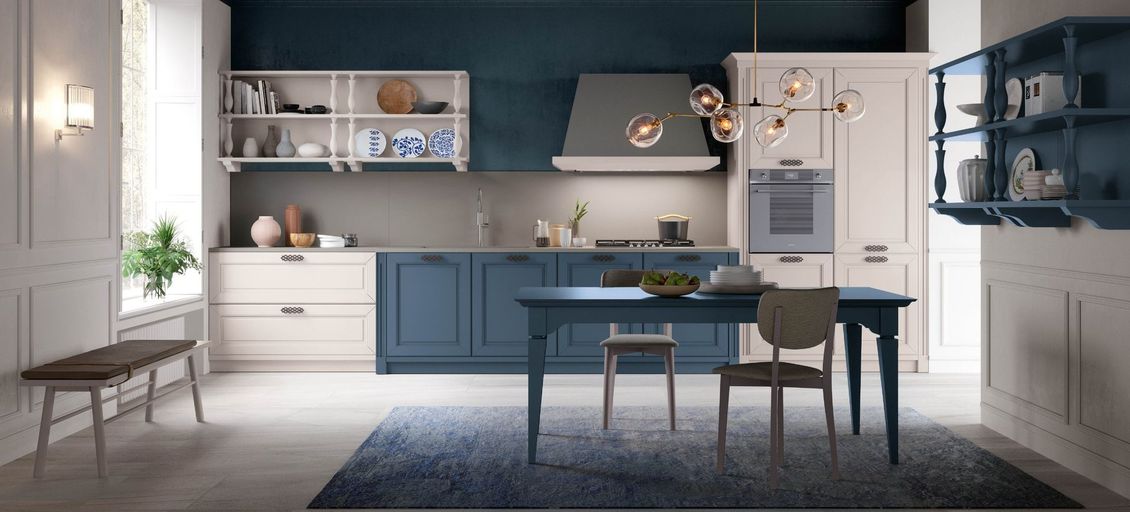 Una cucina con mobili blu, mobili bianchi, un tavolo e sedie.
