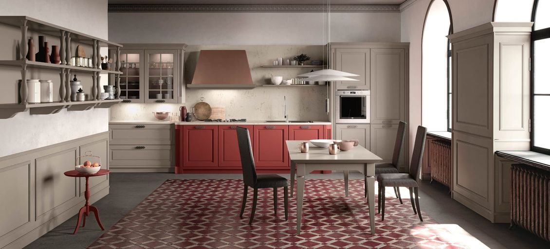 Una cucina con mobili rossi, mobili bianchi, un tavolo e sedie.