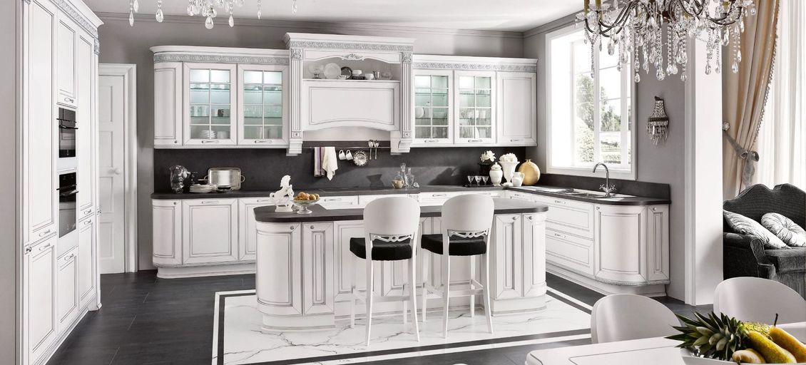 Una cucina con mobili bianchi, ripiani neri e una grande isola.