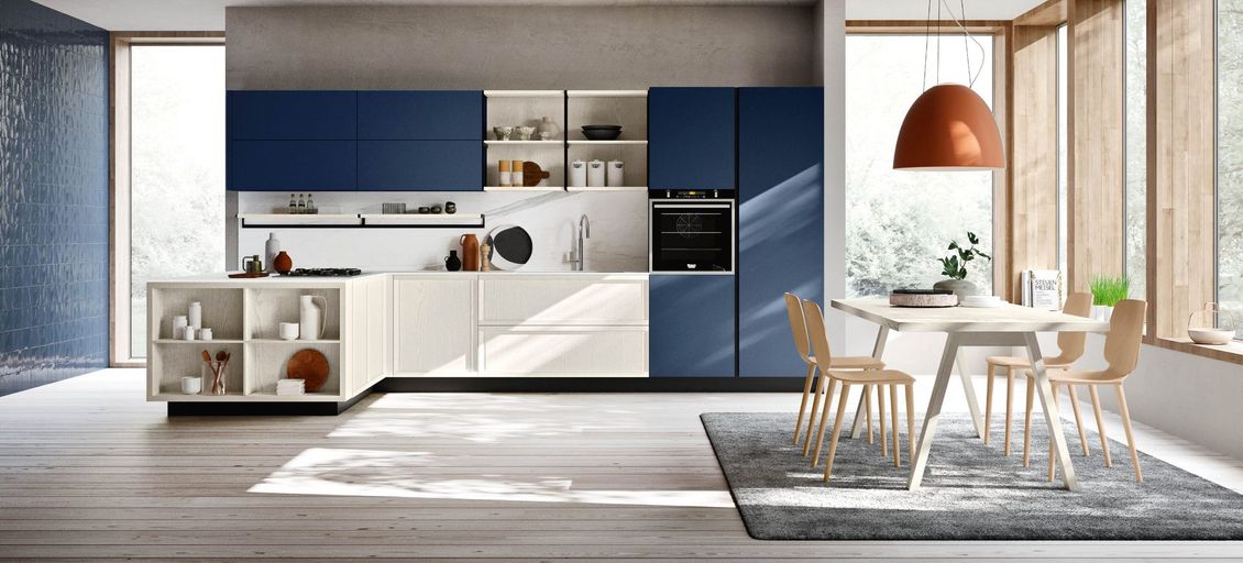 Una cucina con mobili blu e bianchi, tavolo e sedie