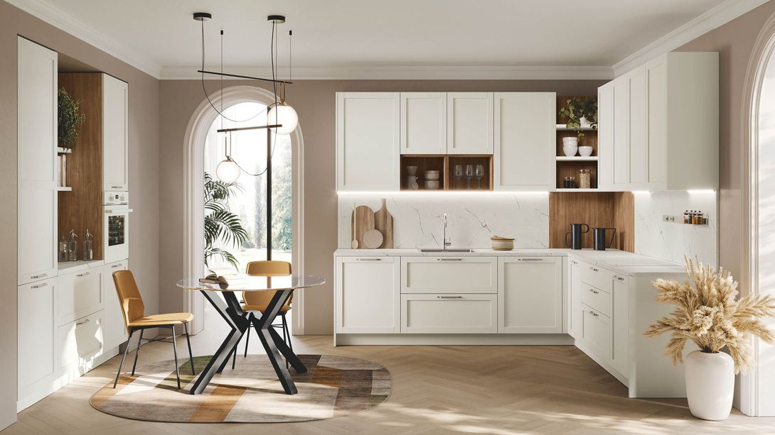 Una cucina con mobili bianchi, tavolo e sedie.