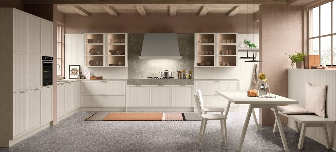 Una cucina con mobili bianchi, tavolo e sedie.