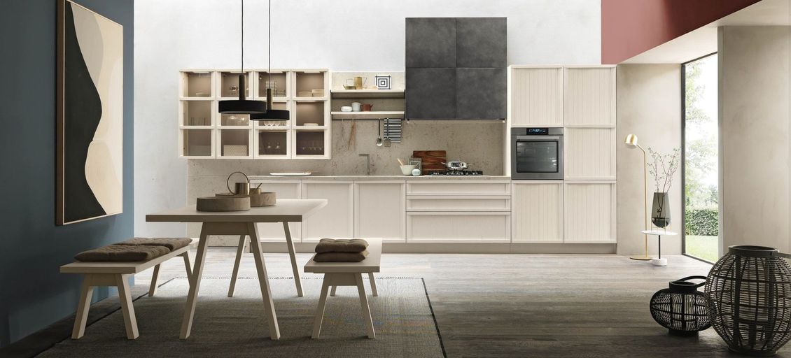 Una cucina con mobili bianchi, tavolo e panche