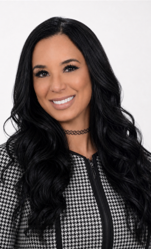 Portrait of a smiling woman with long black hair in a black-and-white houndstooth jacket against a white background