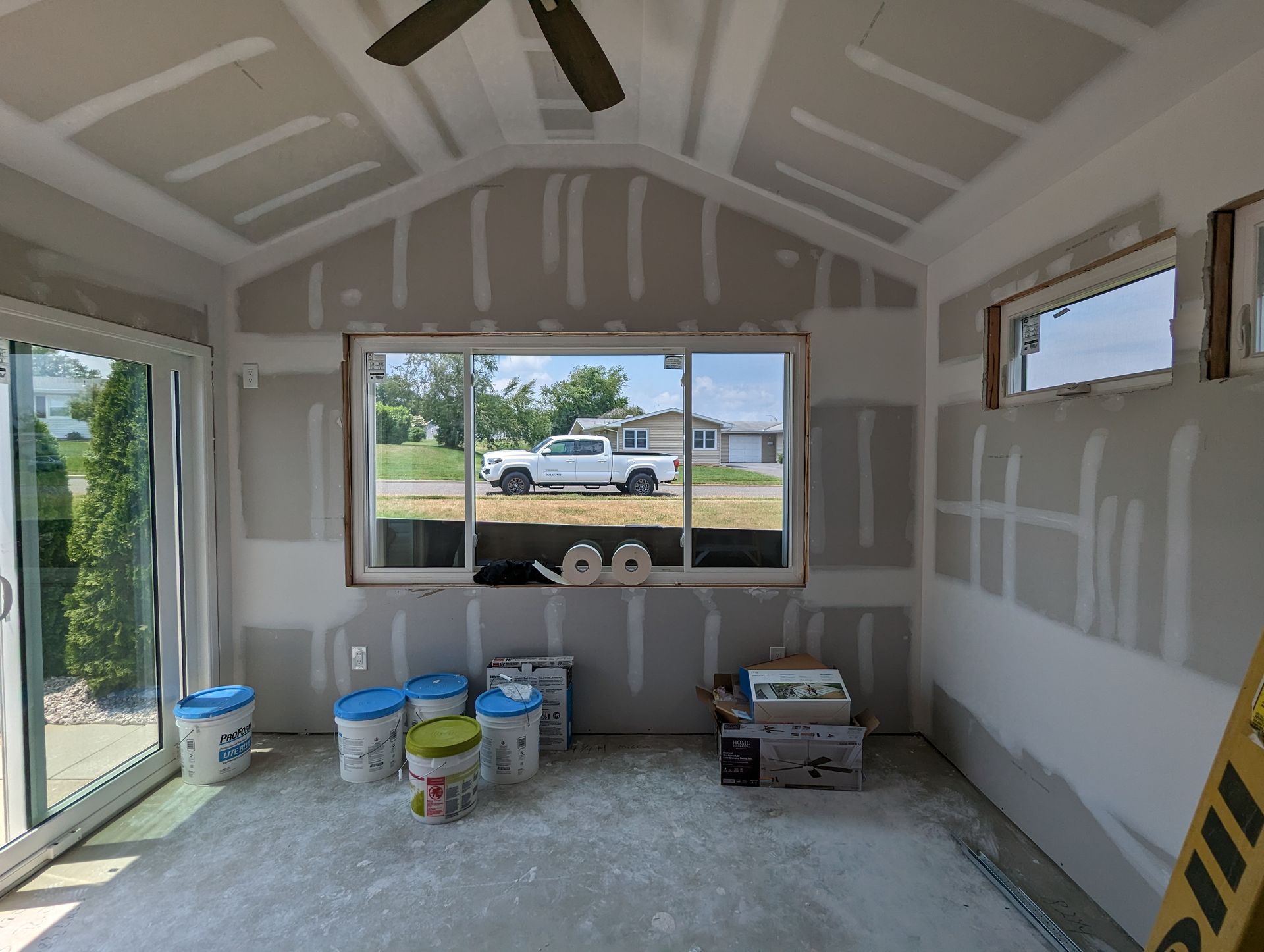 A room with a lot of windows and a ceiling fan