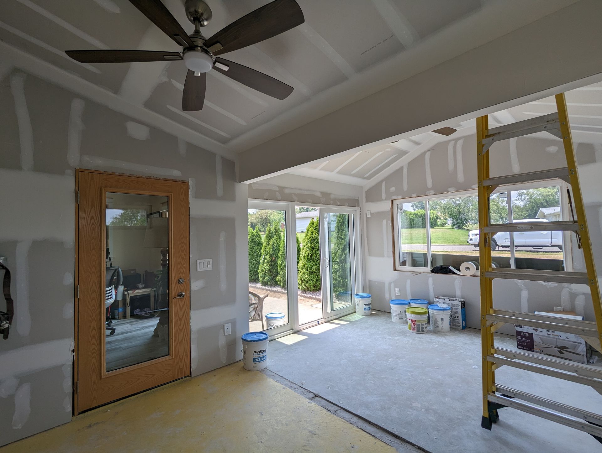 A room with a ceiling fan and a ladder in it