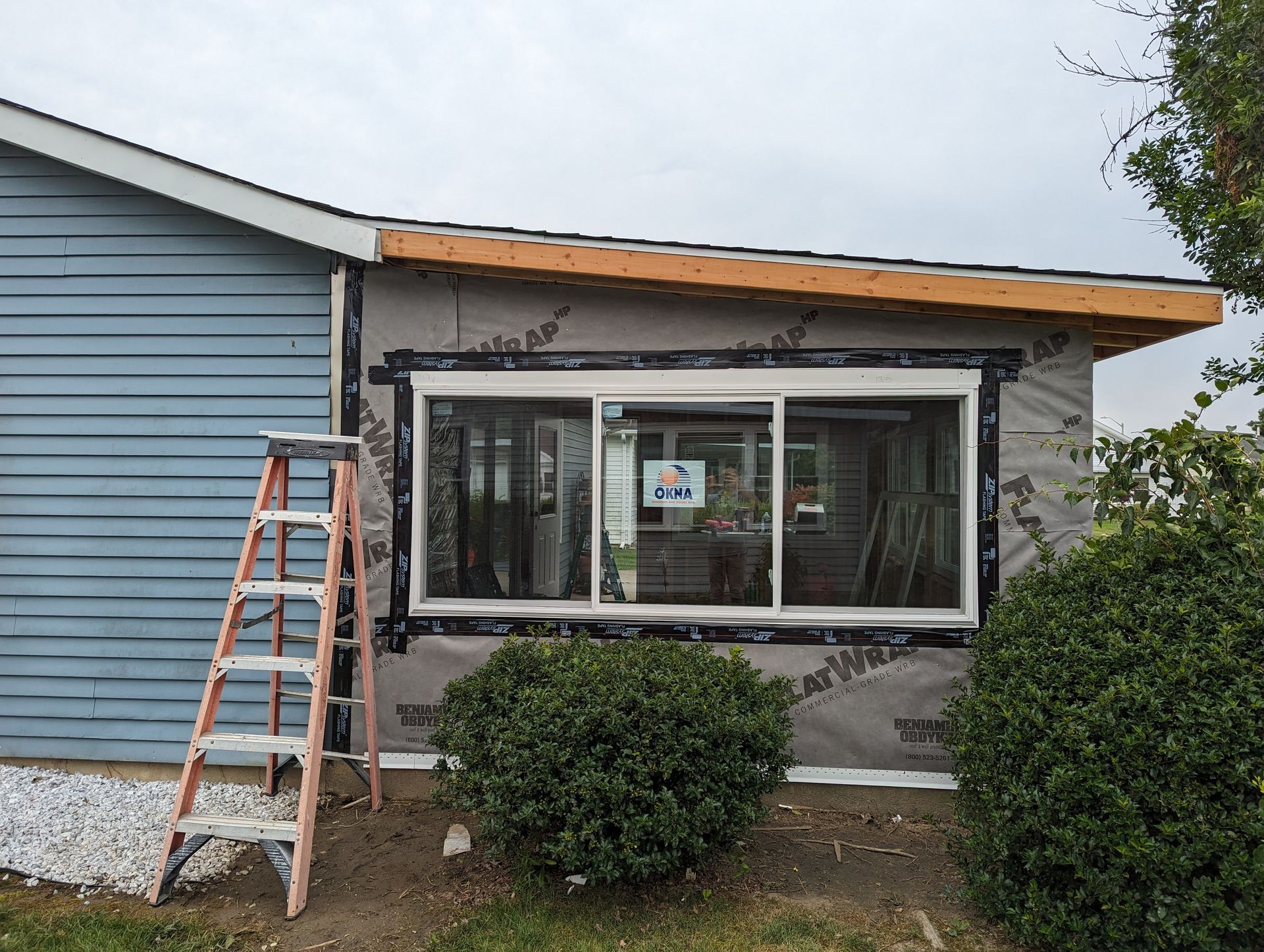 A ladder is sitting in front of a house that is being remodeled.