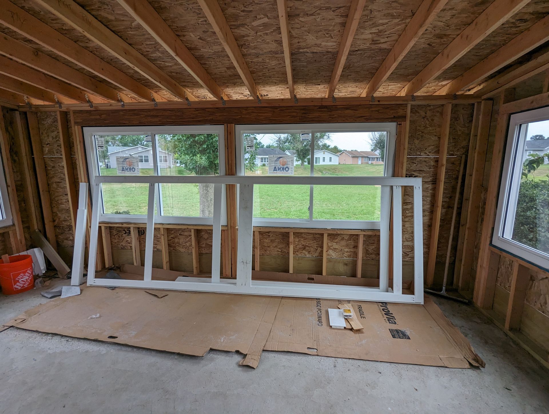 A room with a lot of windows and a bucket on the floor.