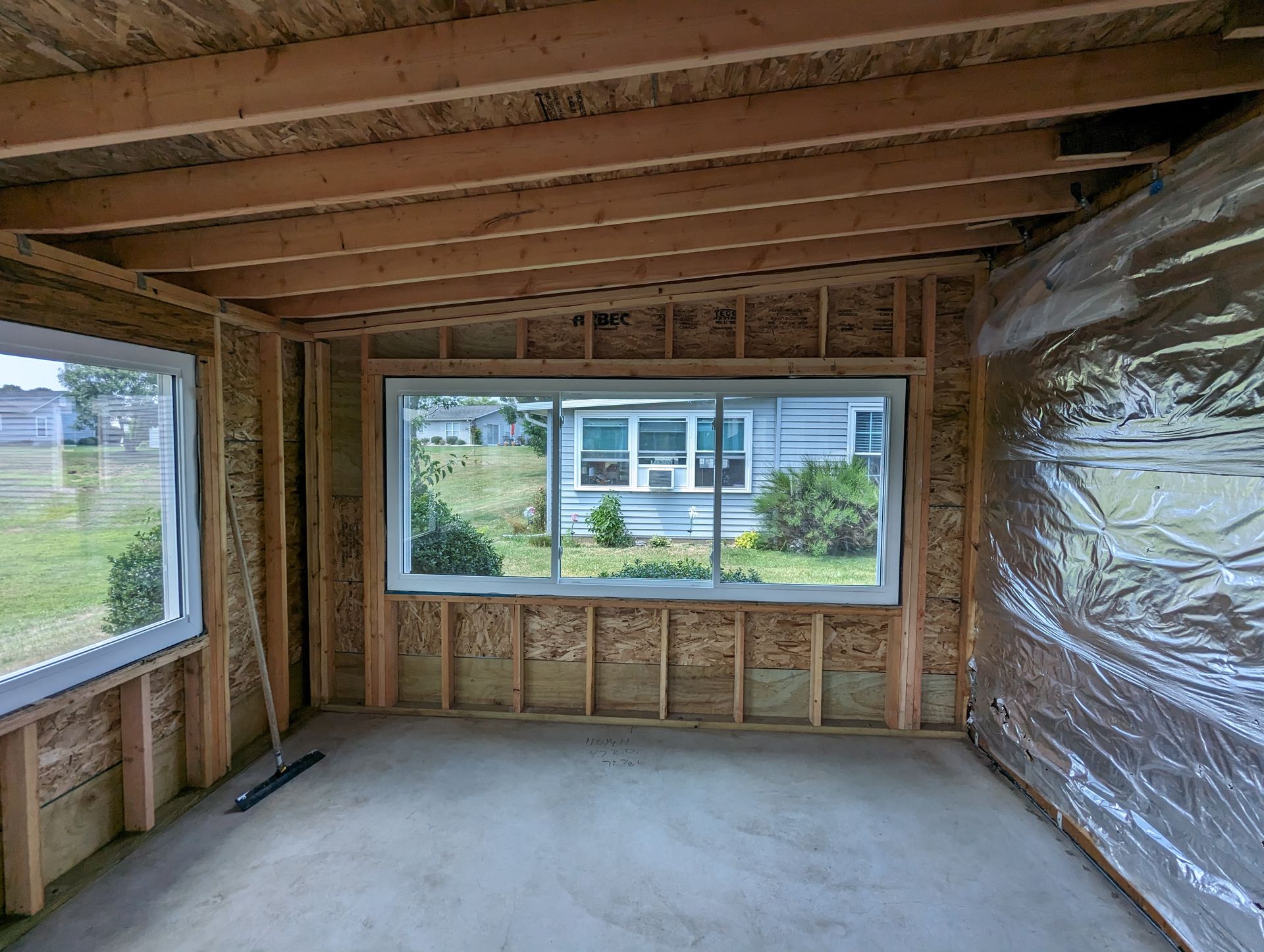 A room with a lot of windows and a house in the background.
