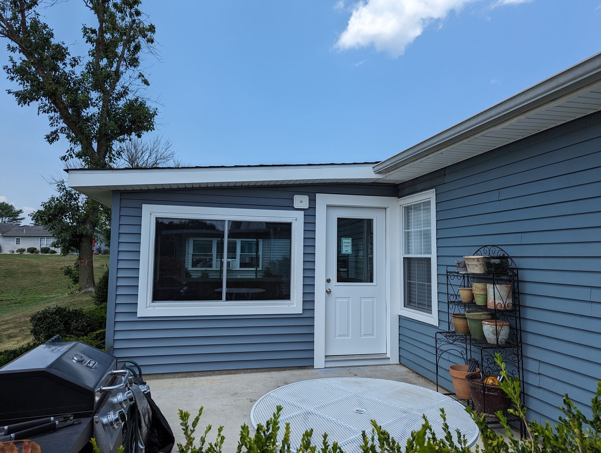A small blue house with a grill in front of it.