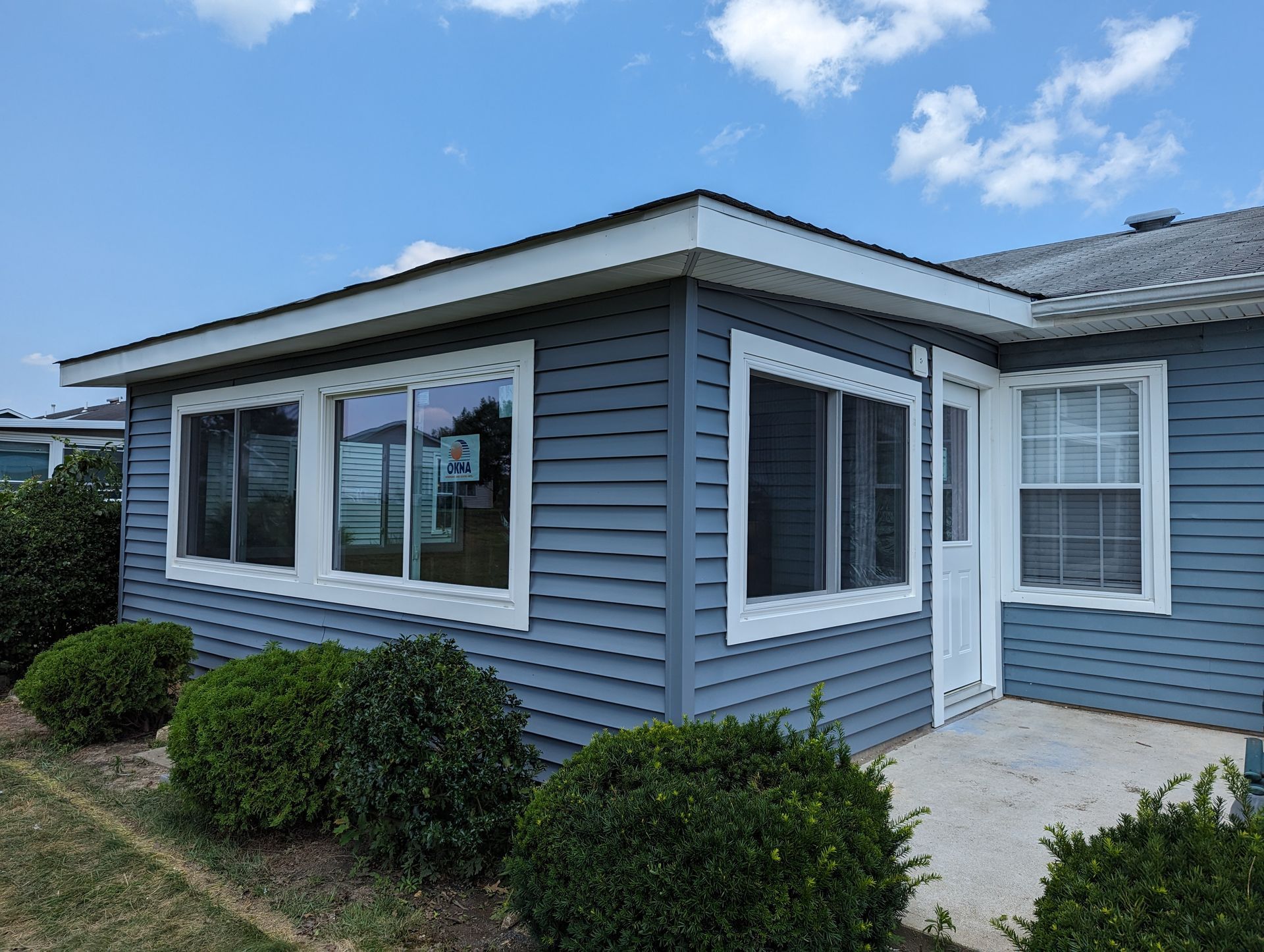A blue mobile home with white trim and windows is for sale.