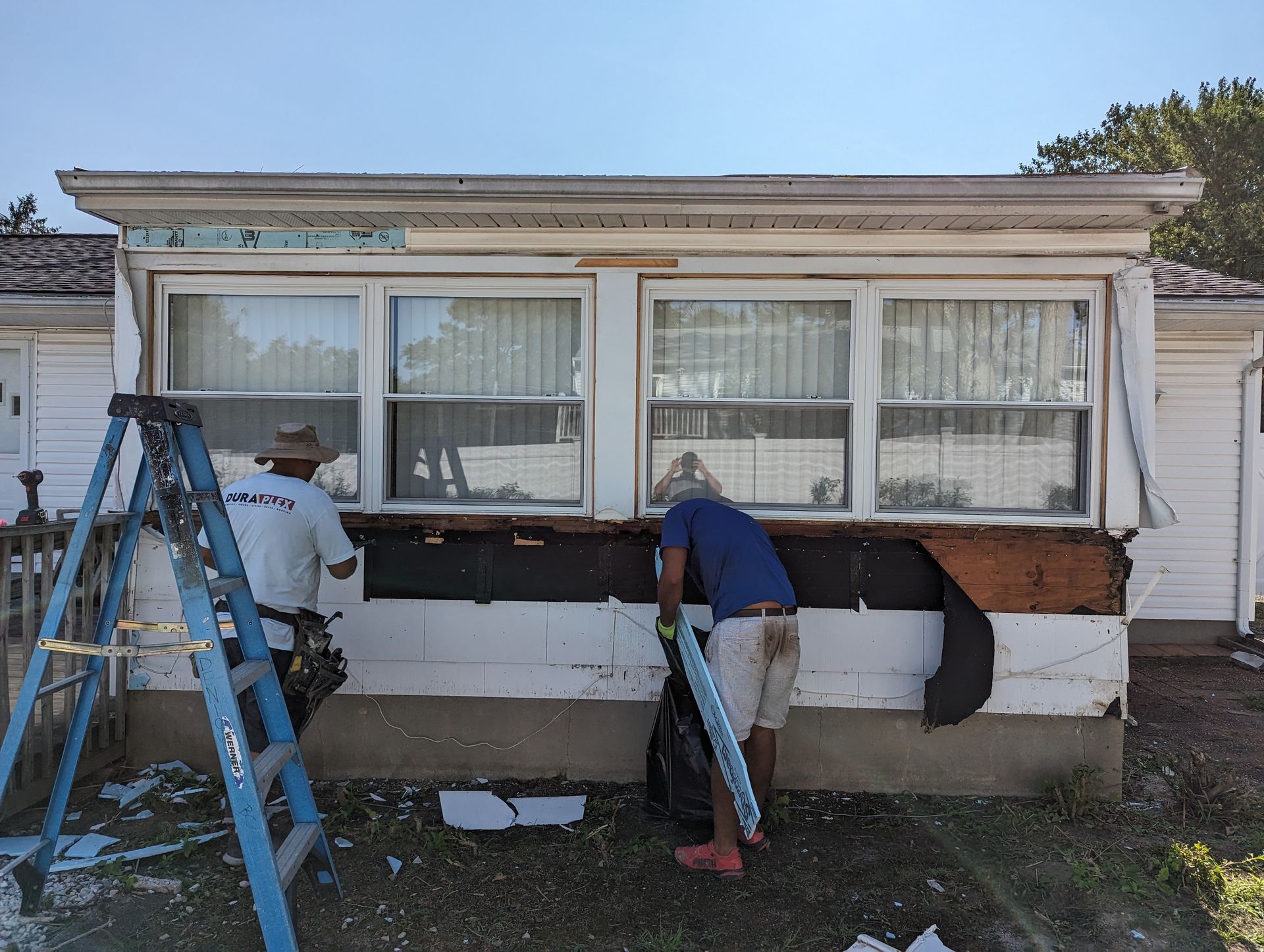 Two men are working on the side of a house.