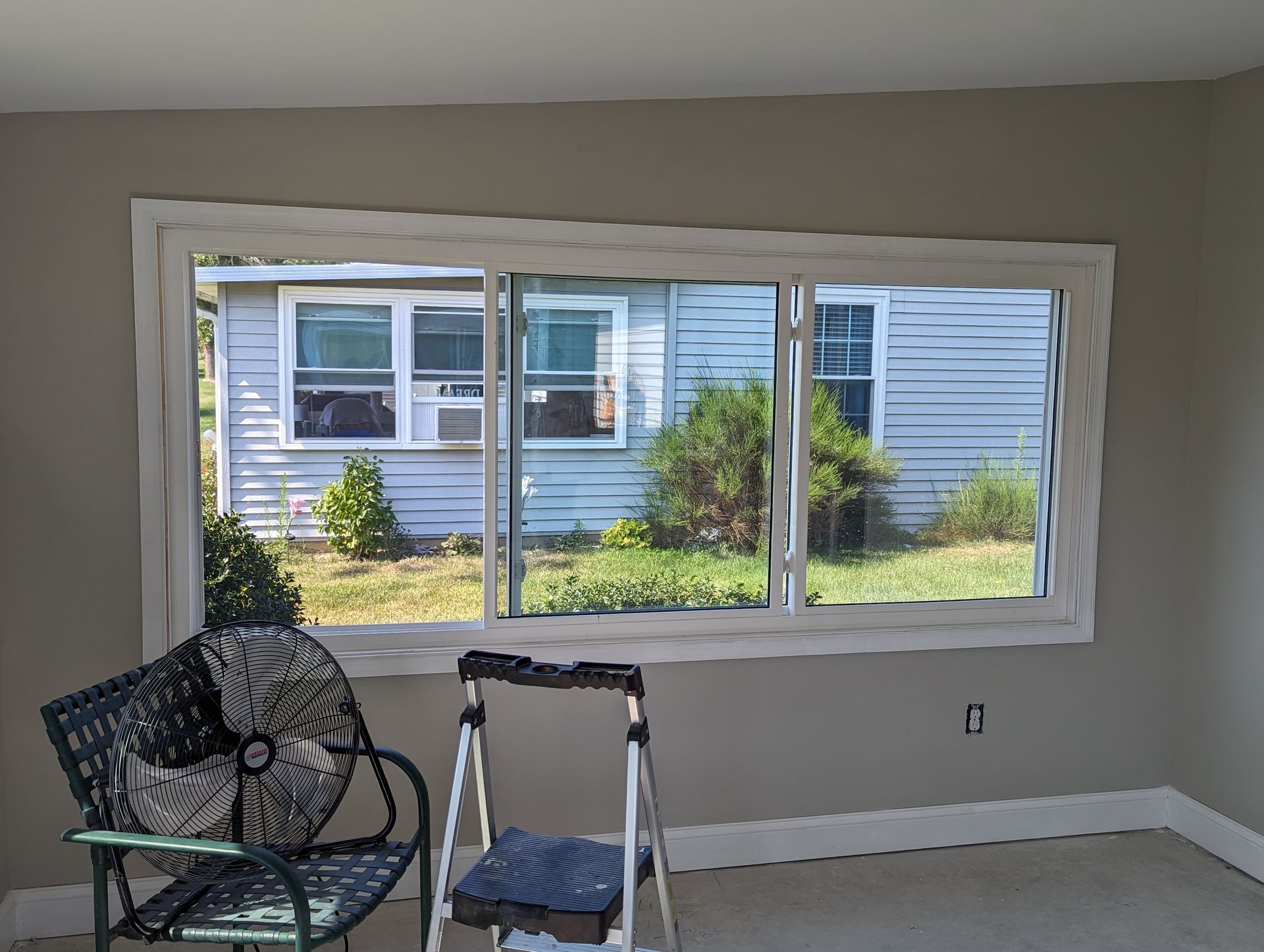 A room with a large window and a chair and ladder