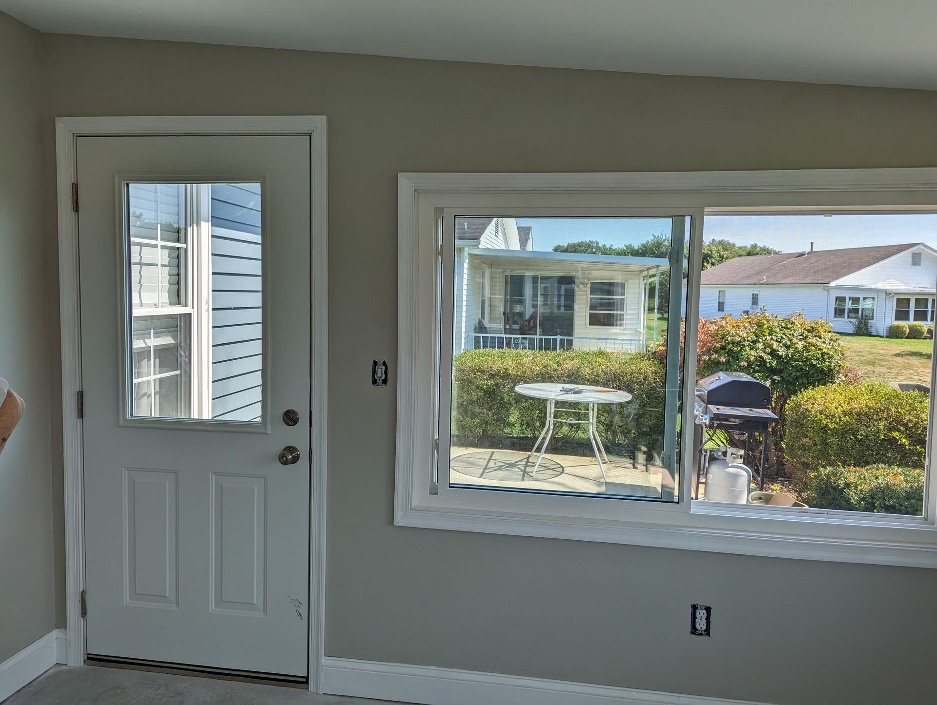 A room with a door and a window with a view of a house.