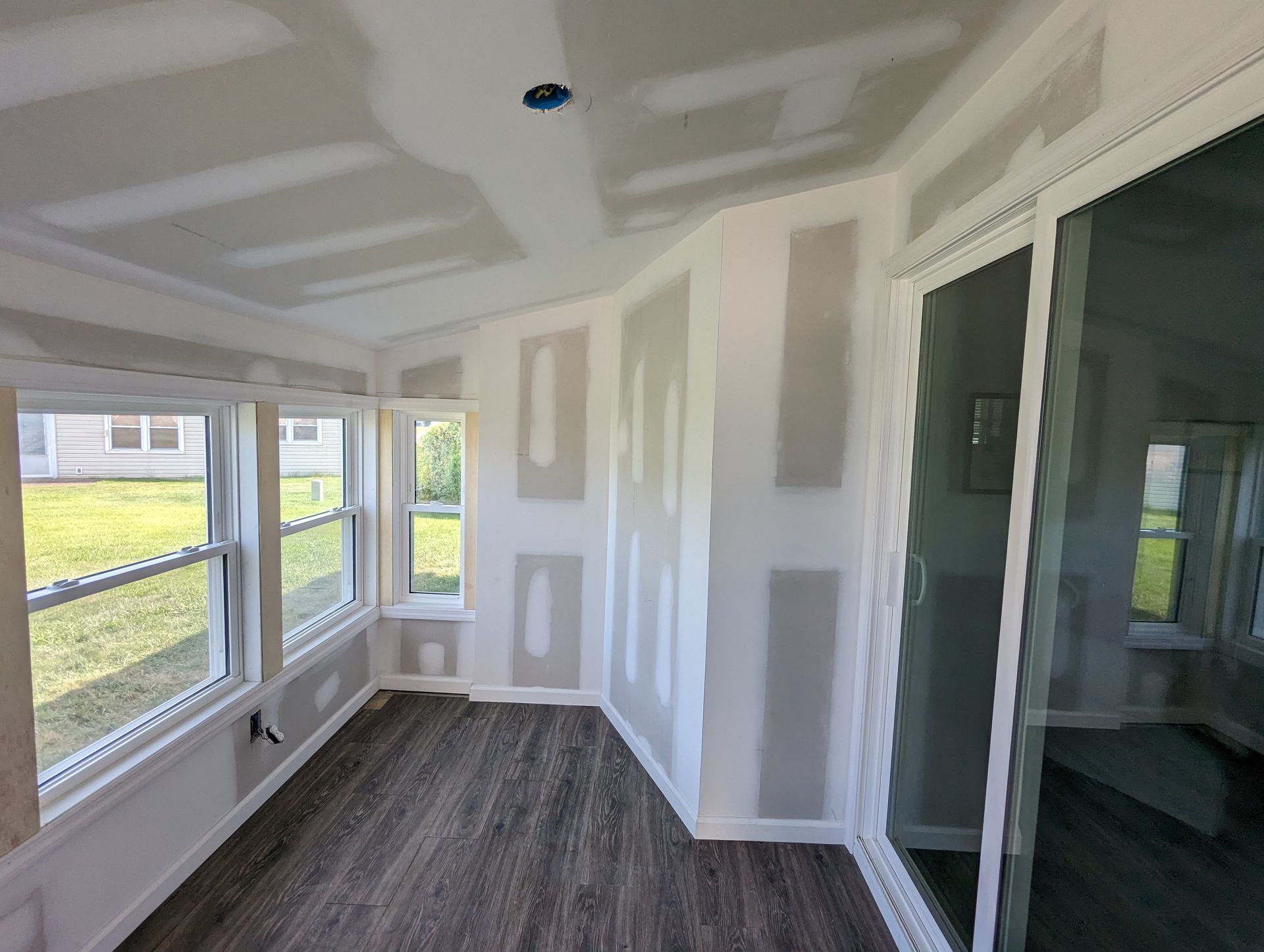 A room with a lot of windows and drywall on the walls.