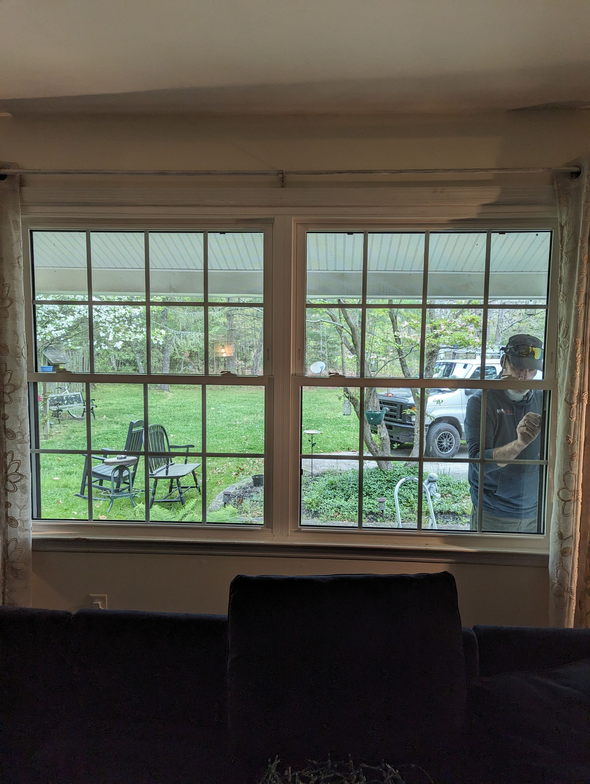 A man is standing in front of a window in a living room.