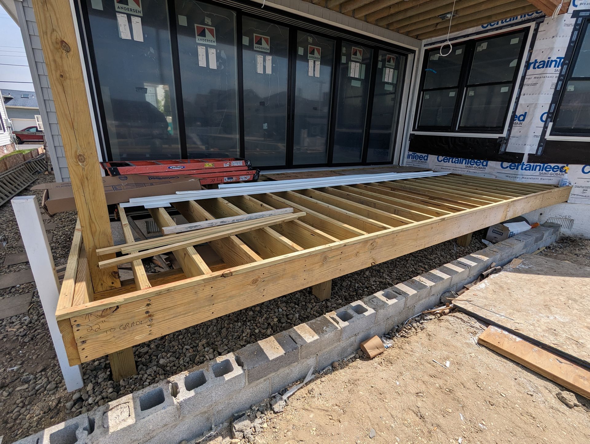 A wooden deck is being built in front of a house under construction.