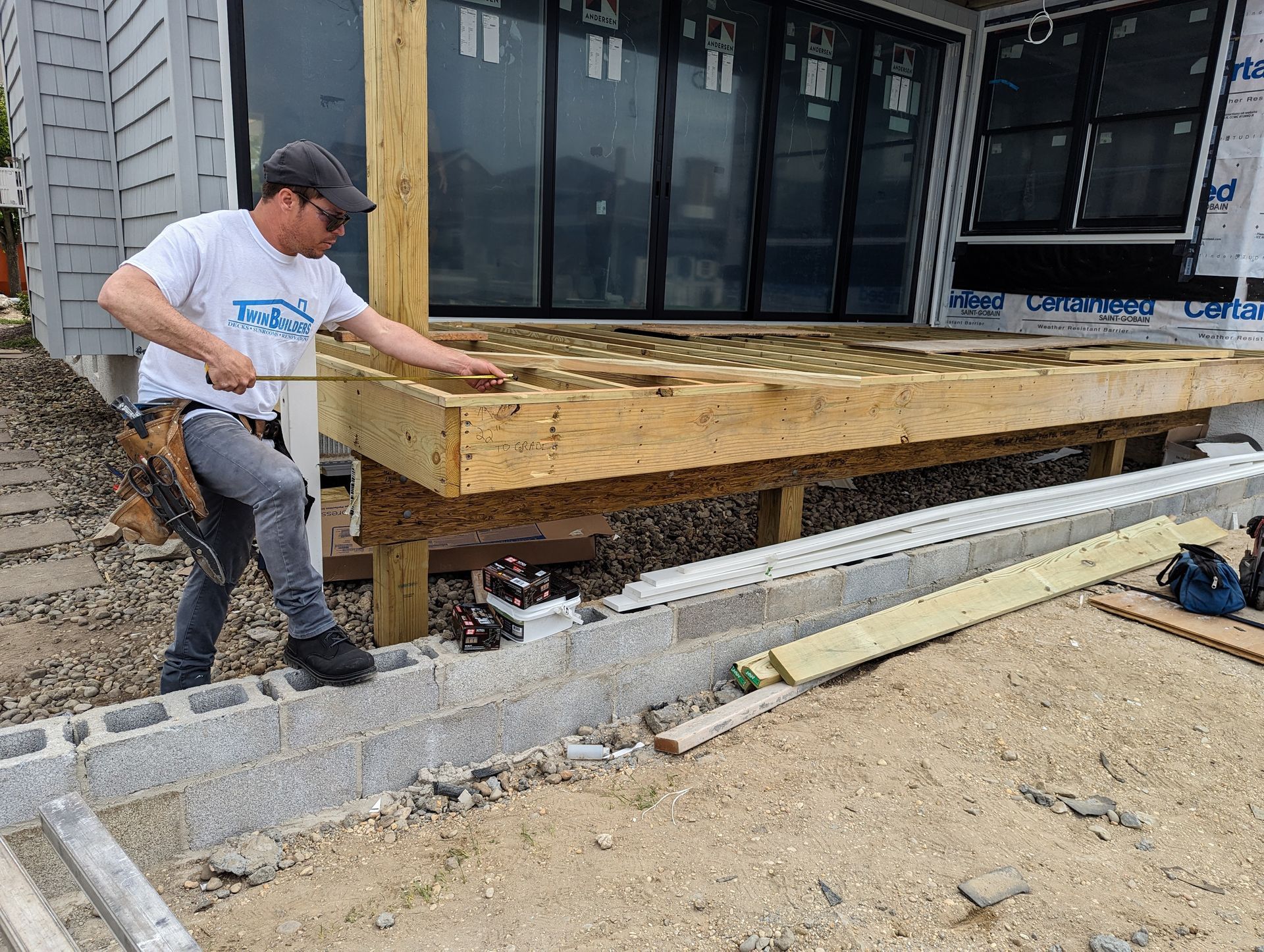 A man is measuring a wooden deck with a tape measure.