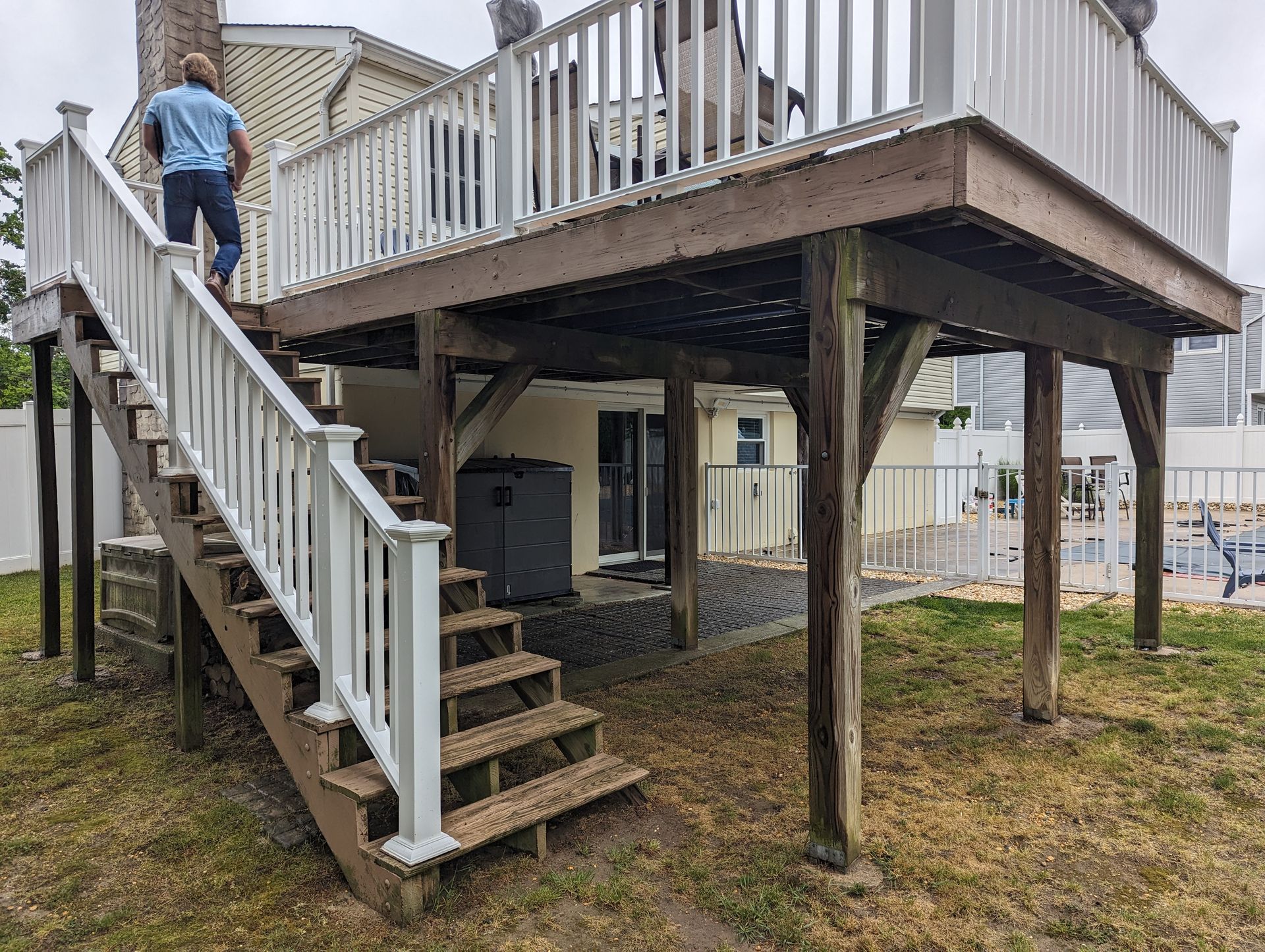 A man is standing on top of a wooden deck with stairs leading up to it.