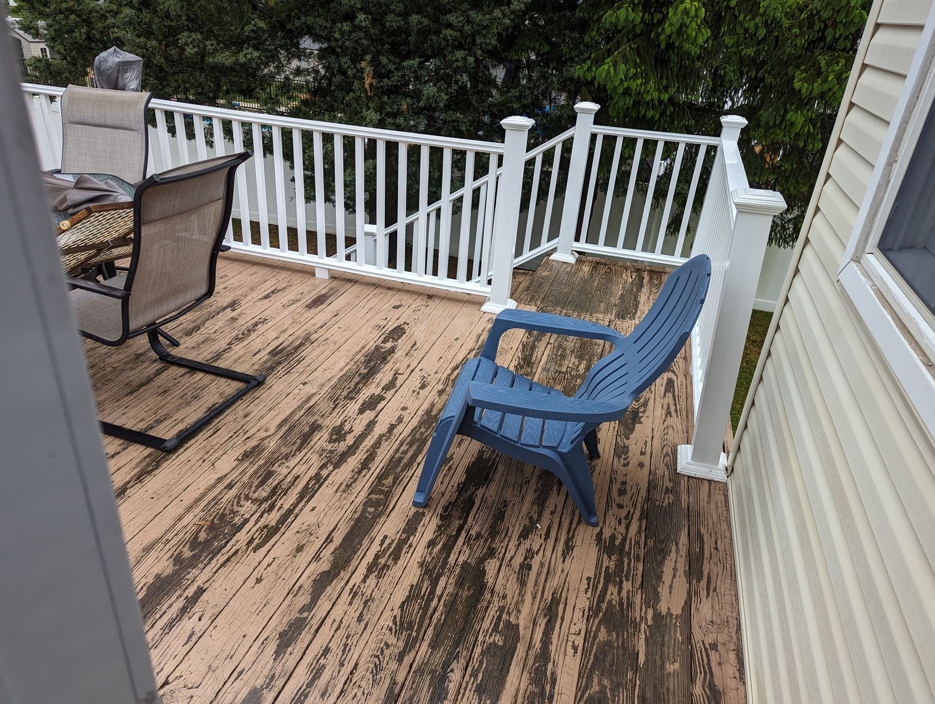 A blue chair is sitting on a wooden deck next to a white railing.