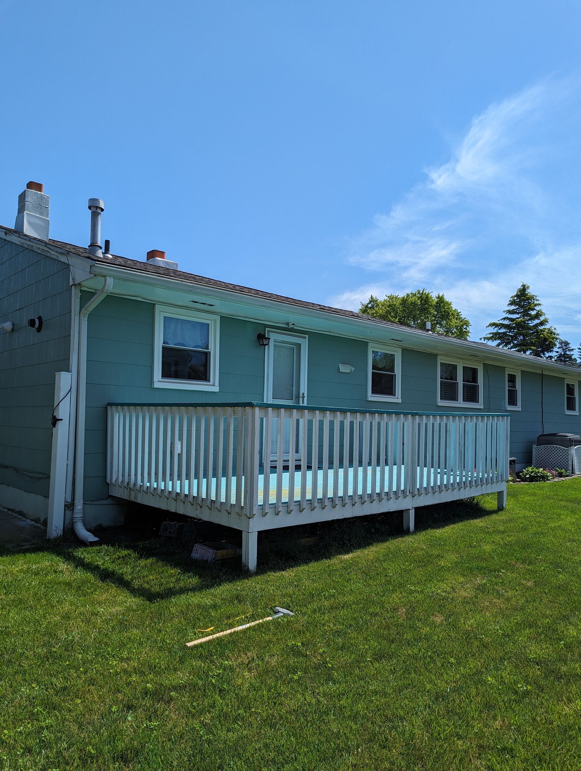 A house with a deck in the backyard on a sunny day.