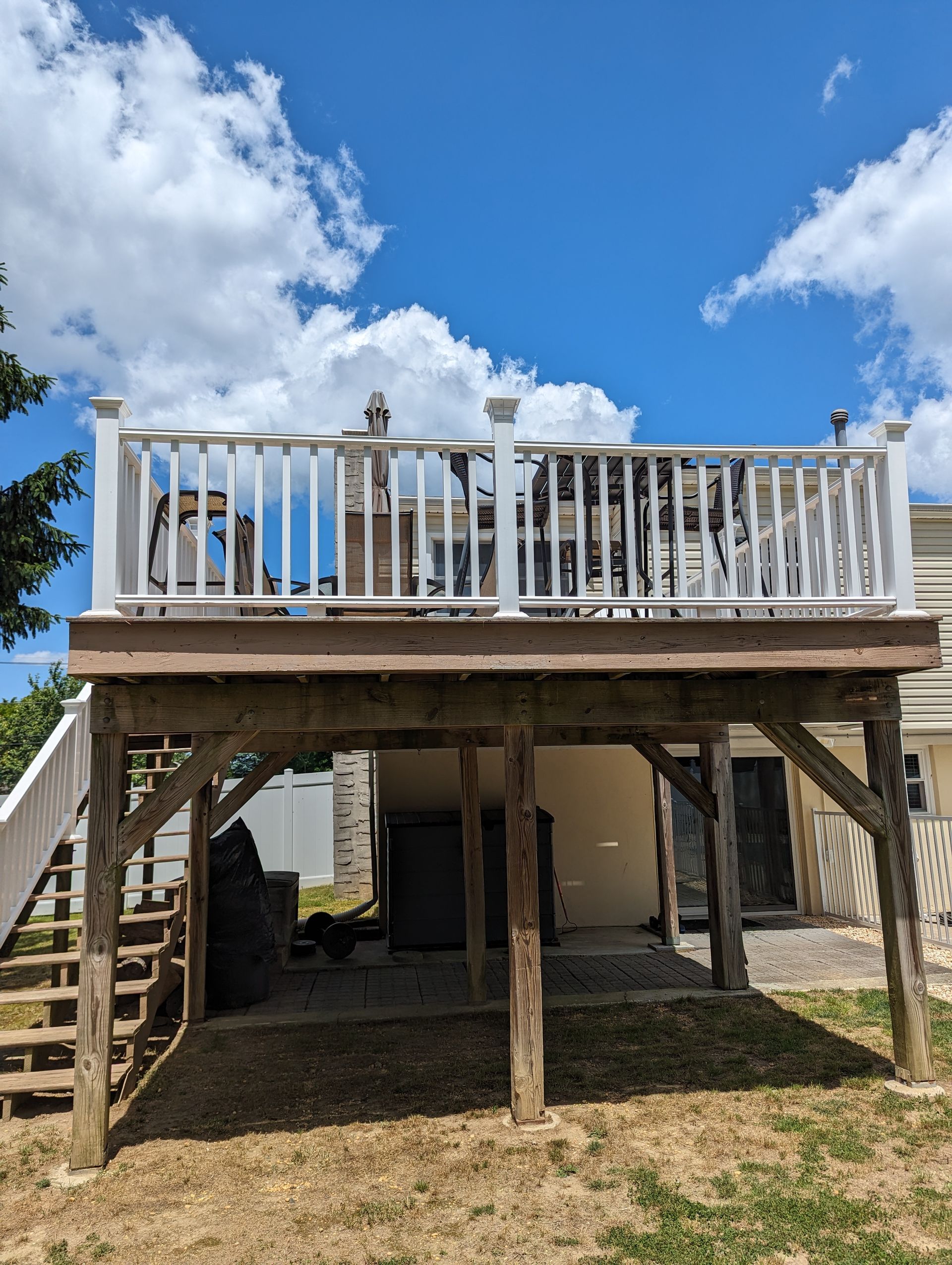 A large wooden deck with a white railing is sitting on top of a house.