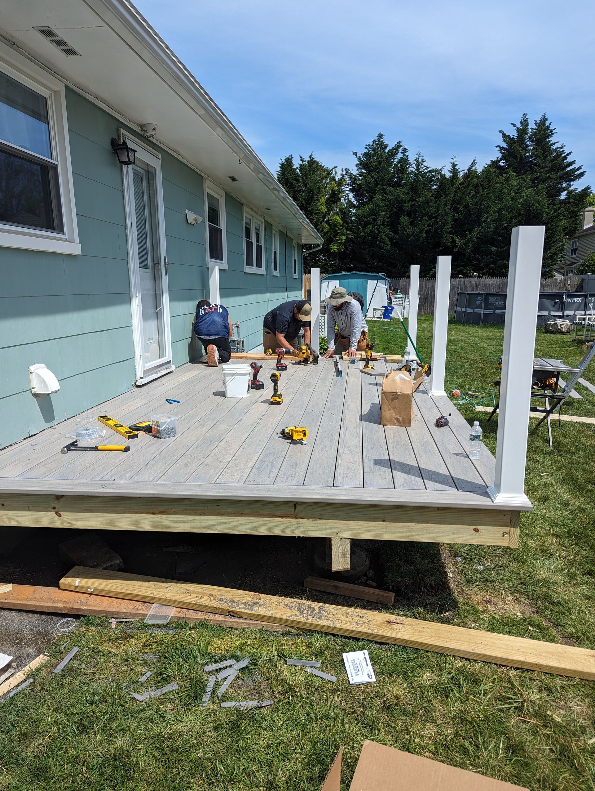 A group of men are working on a deck in front of a house.