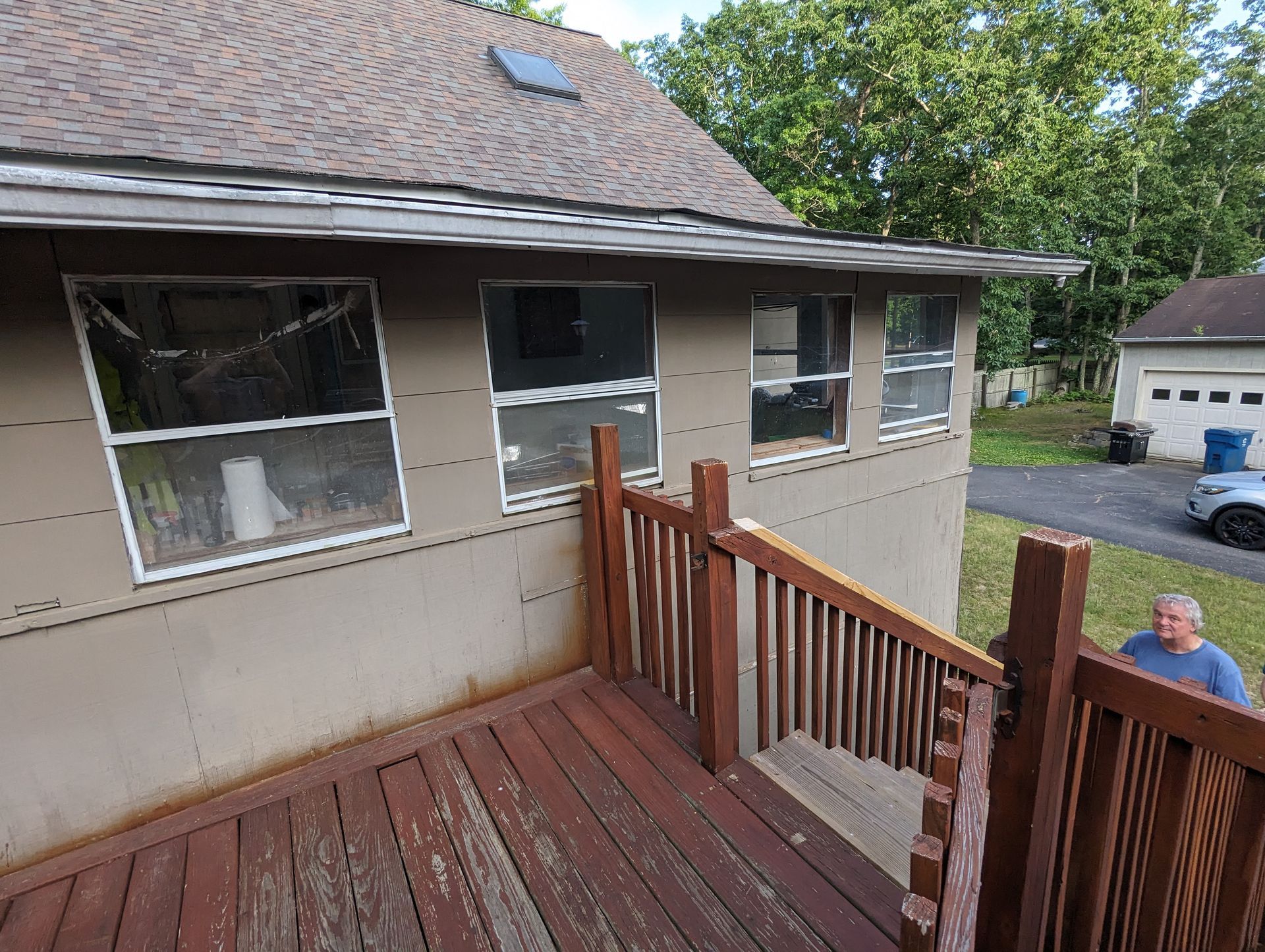 A man is standing on a wooden deck next to a house.