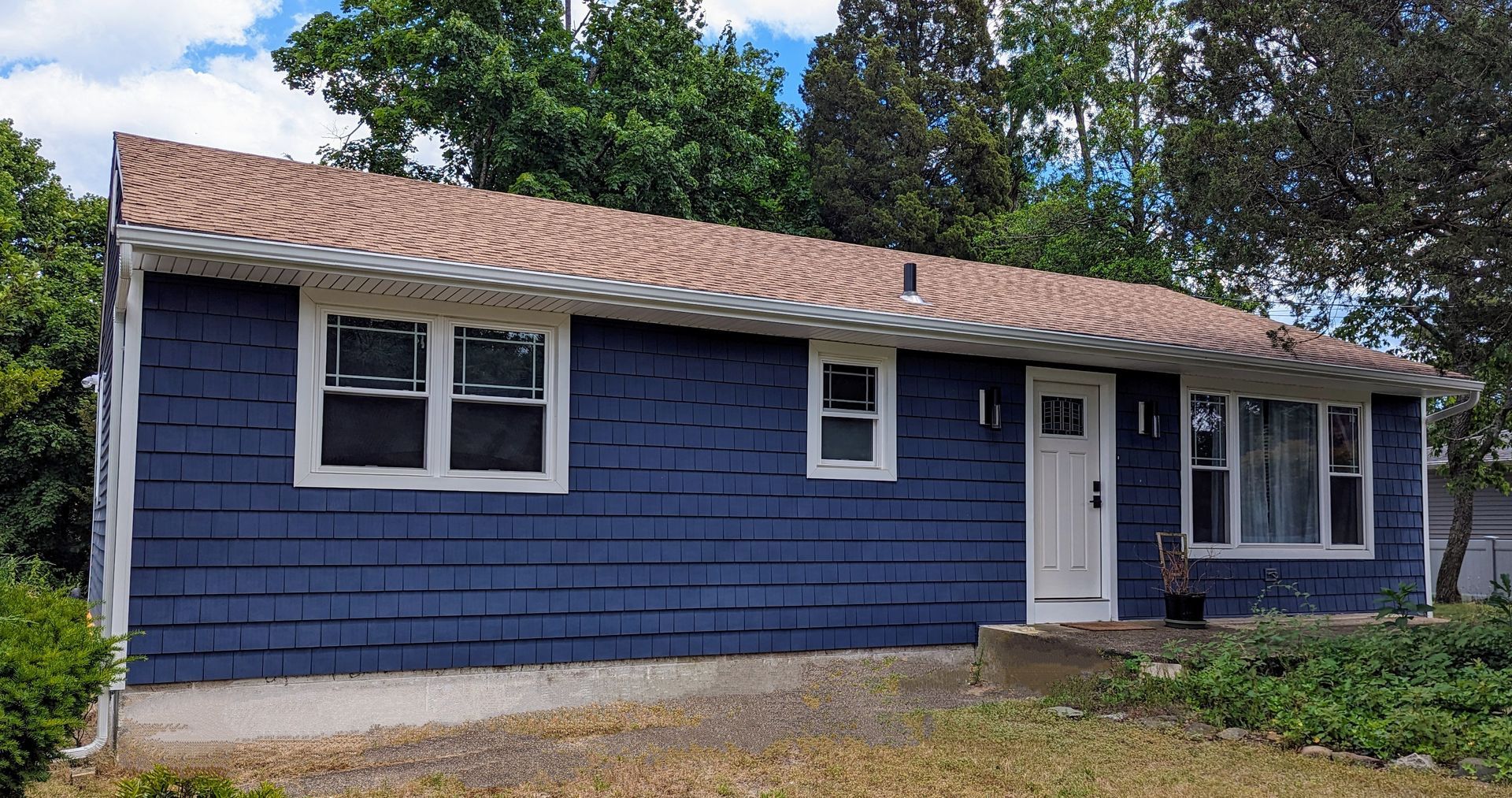 A blue brick house with a white door and windows is for sale.