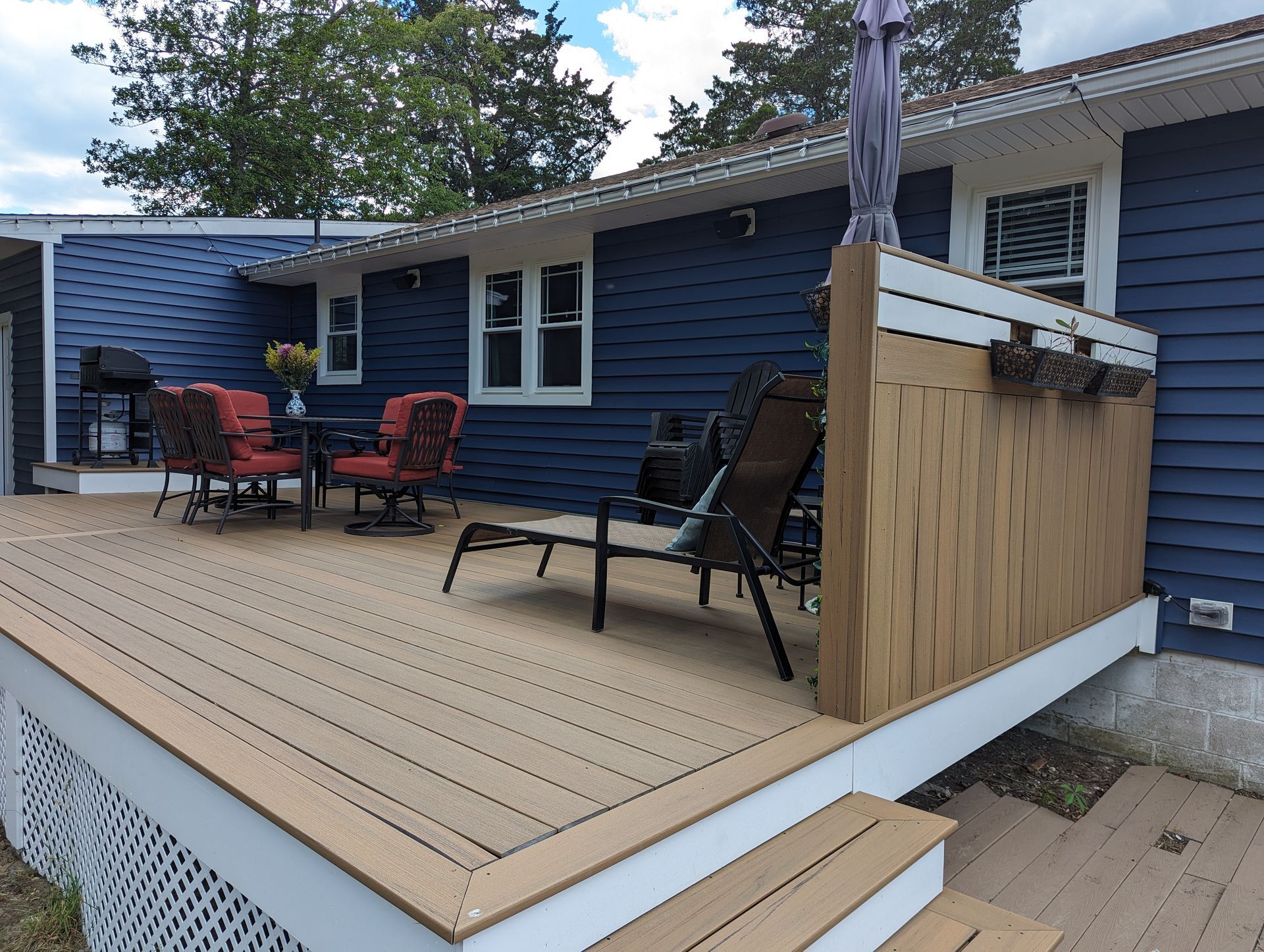 A blue house with a deck with a table and chairs on it
