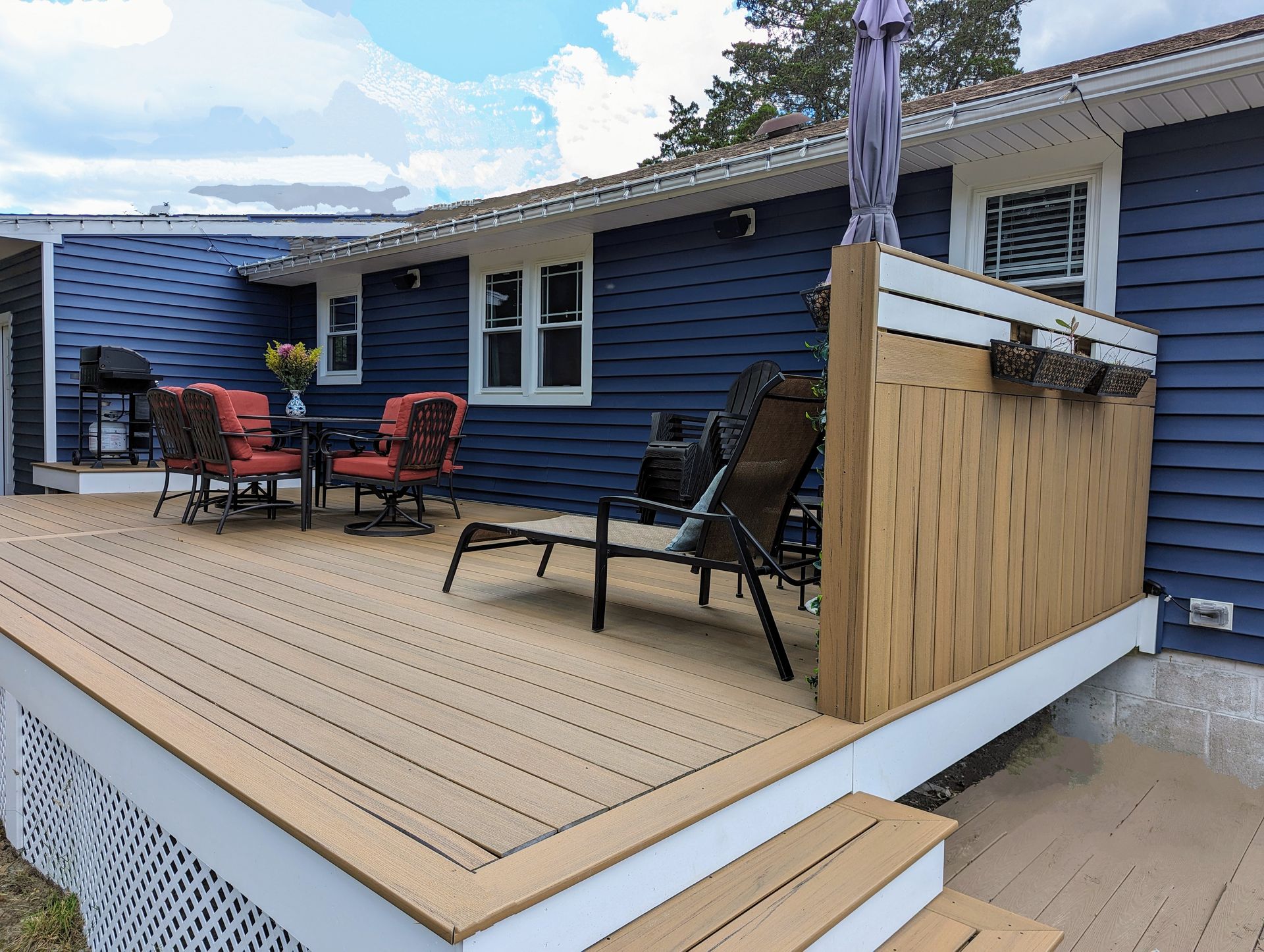A blue house with a wooden deck with a table and chairs on it.