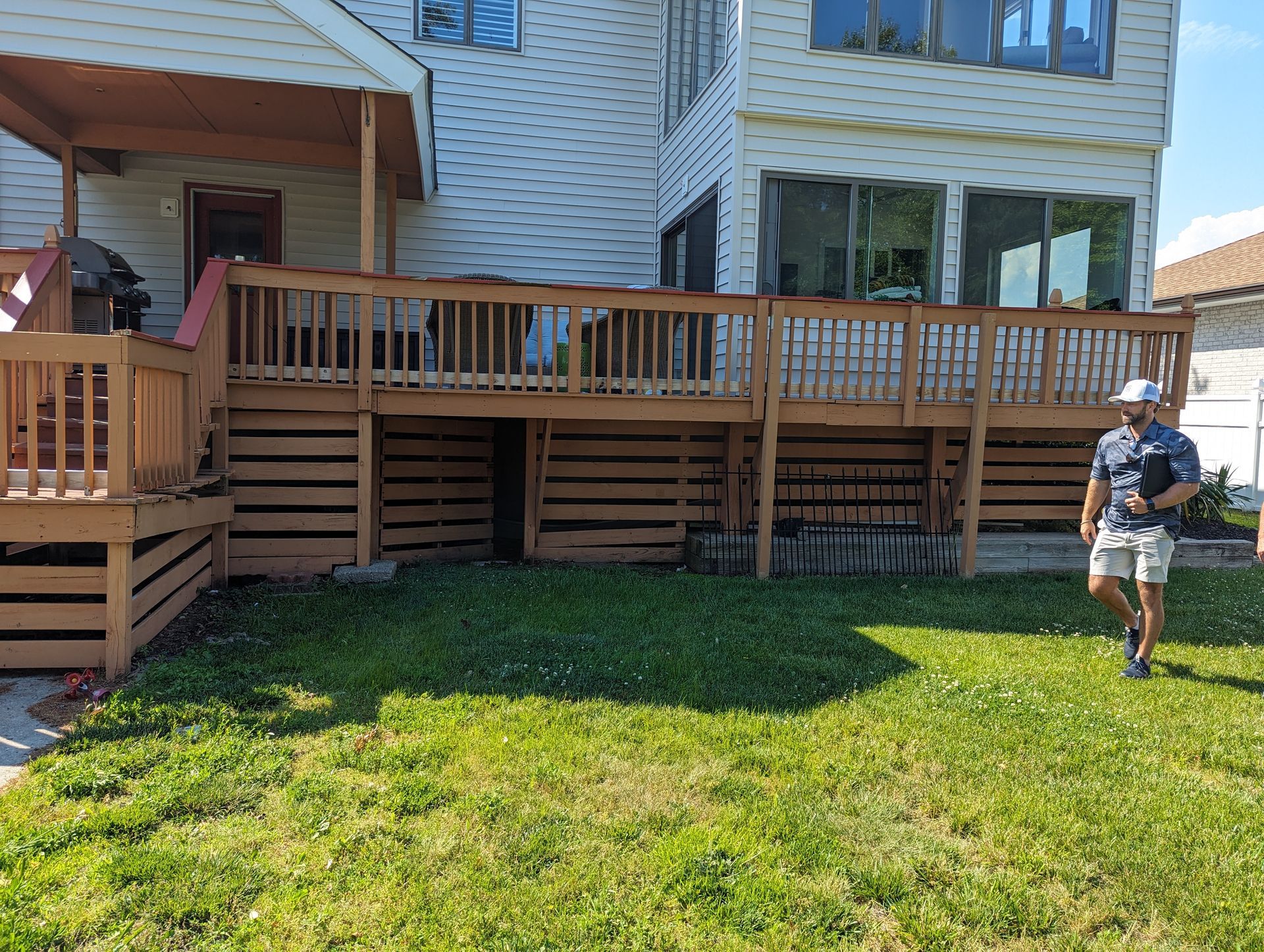 A man is standing in front of a large wooden deck.